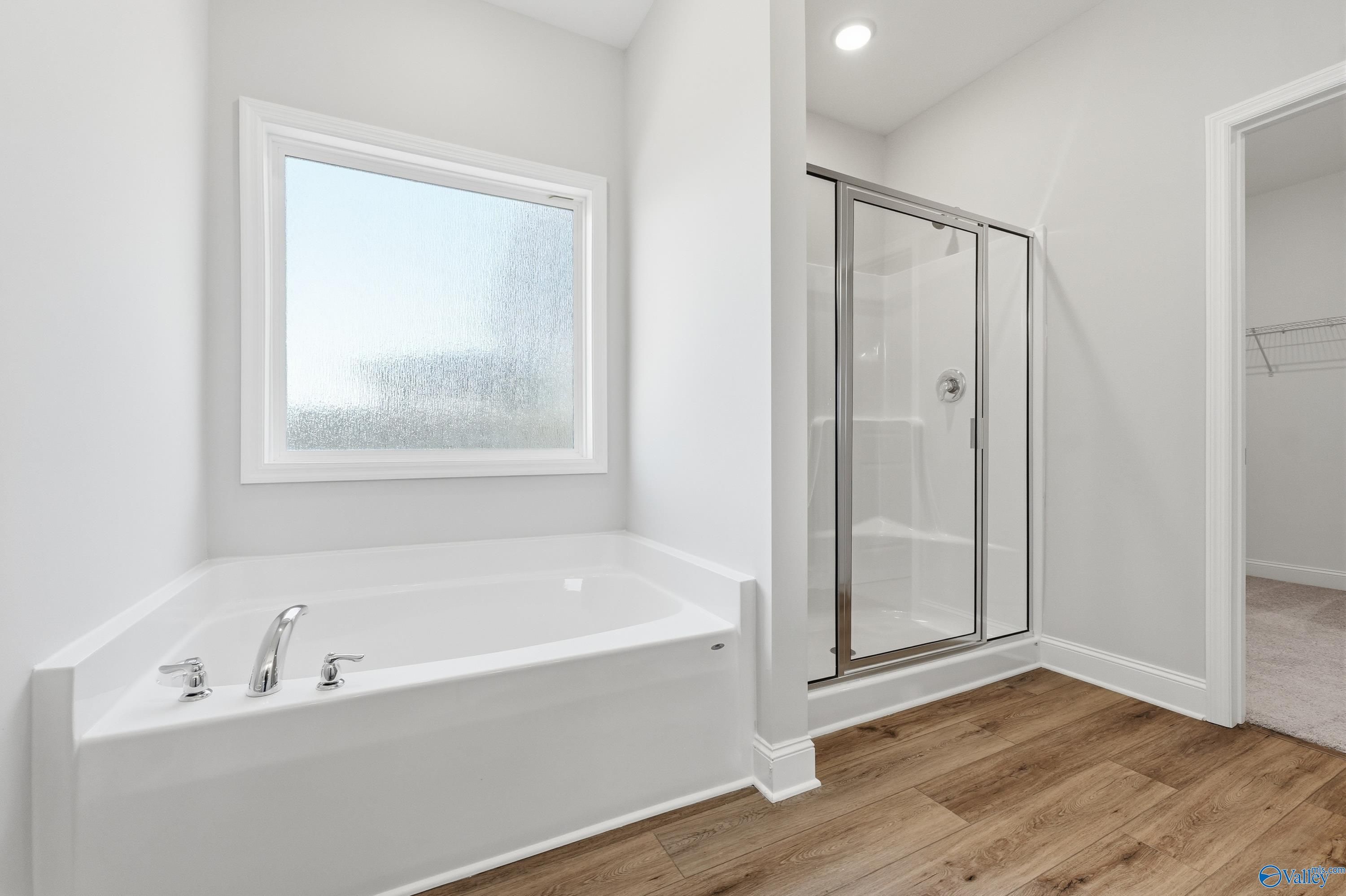 Luxurious master bathroom featuring corner tub, glass shower, and frosted window in Davidson Homes The Everett, Harvest AL