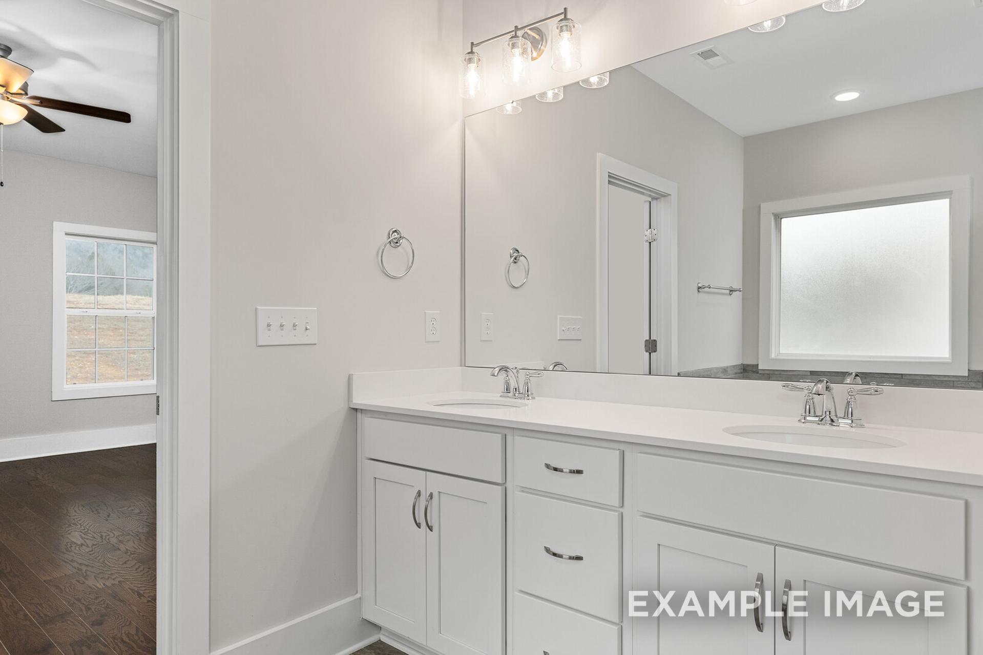 Spacious master bathroom in The Rockford by Davidson Homes featuring double vanity, large mirror, and frosted window
