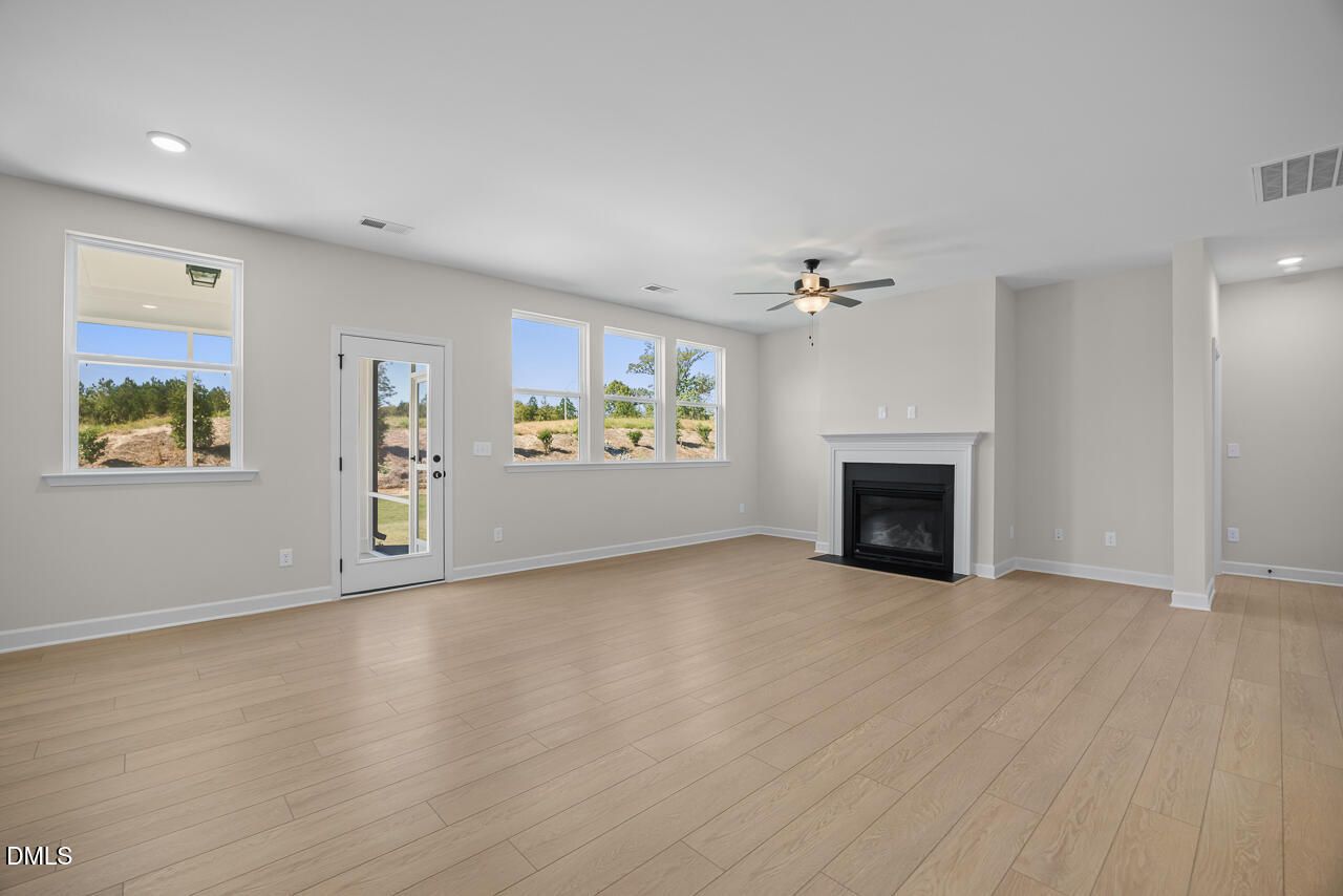 Bright great room with hardwood floors, fireplace, ceiling fan, and backyard views in Davidson Homes The Ashport M, Wendell NC