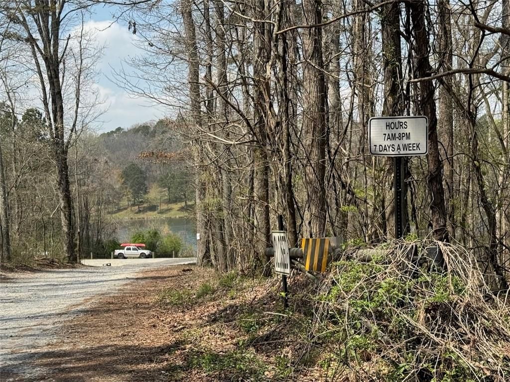 Wooded gravel entrance to The Bluffs community in Canton, Georgia, with 7AM-5PM hours sign near Davidson Homes sales office