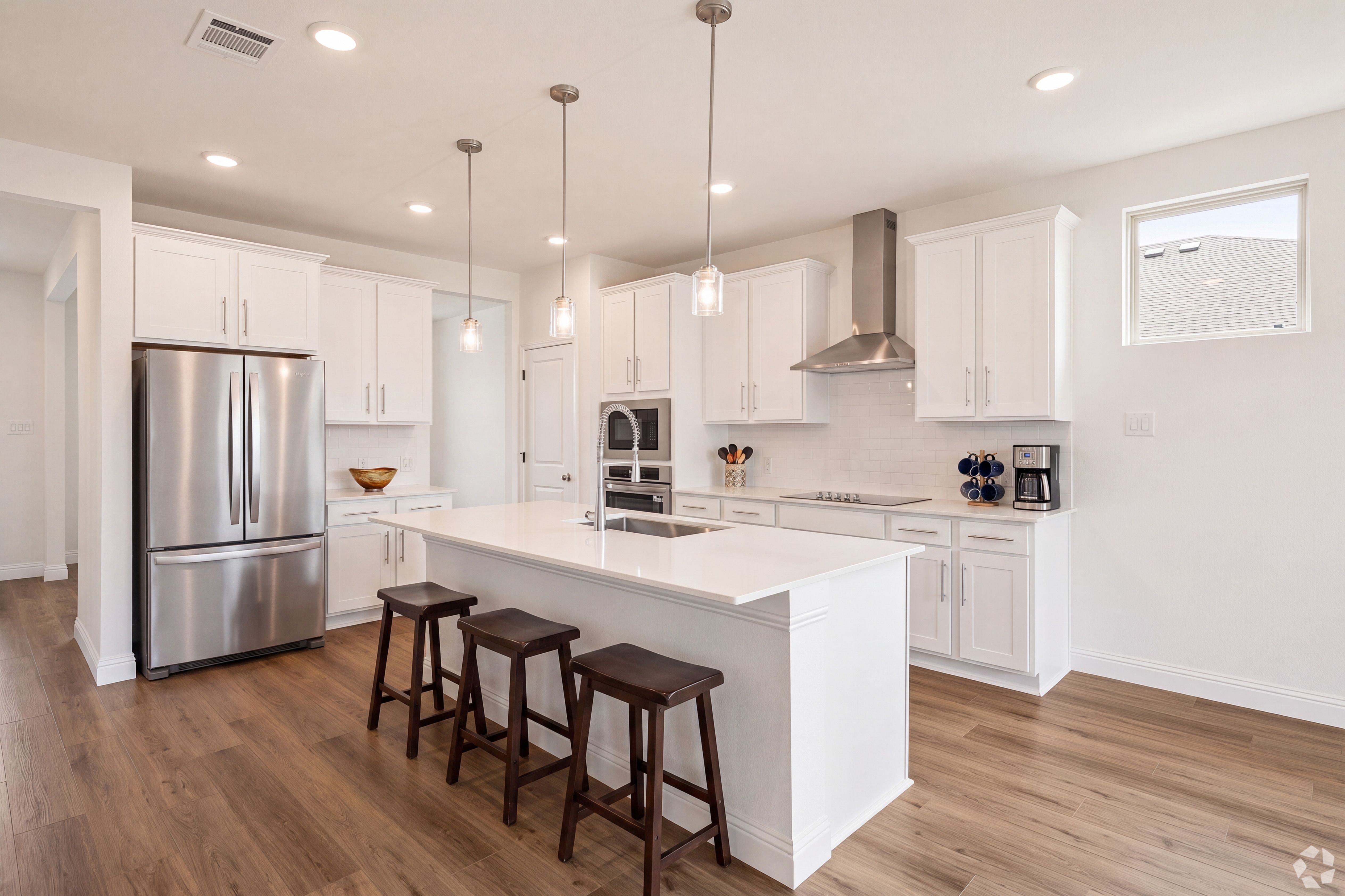 Open concept kitchen with white cabinets and stainless appliances at Mercer Meadows in Royse City, TX