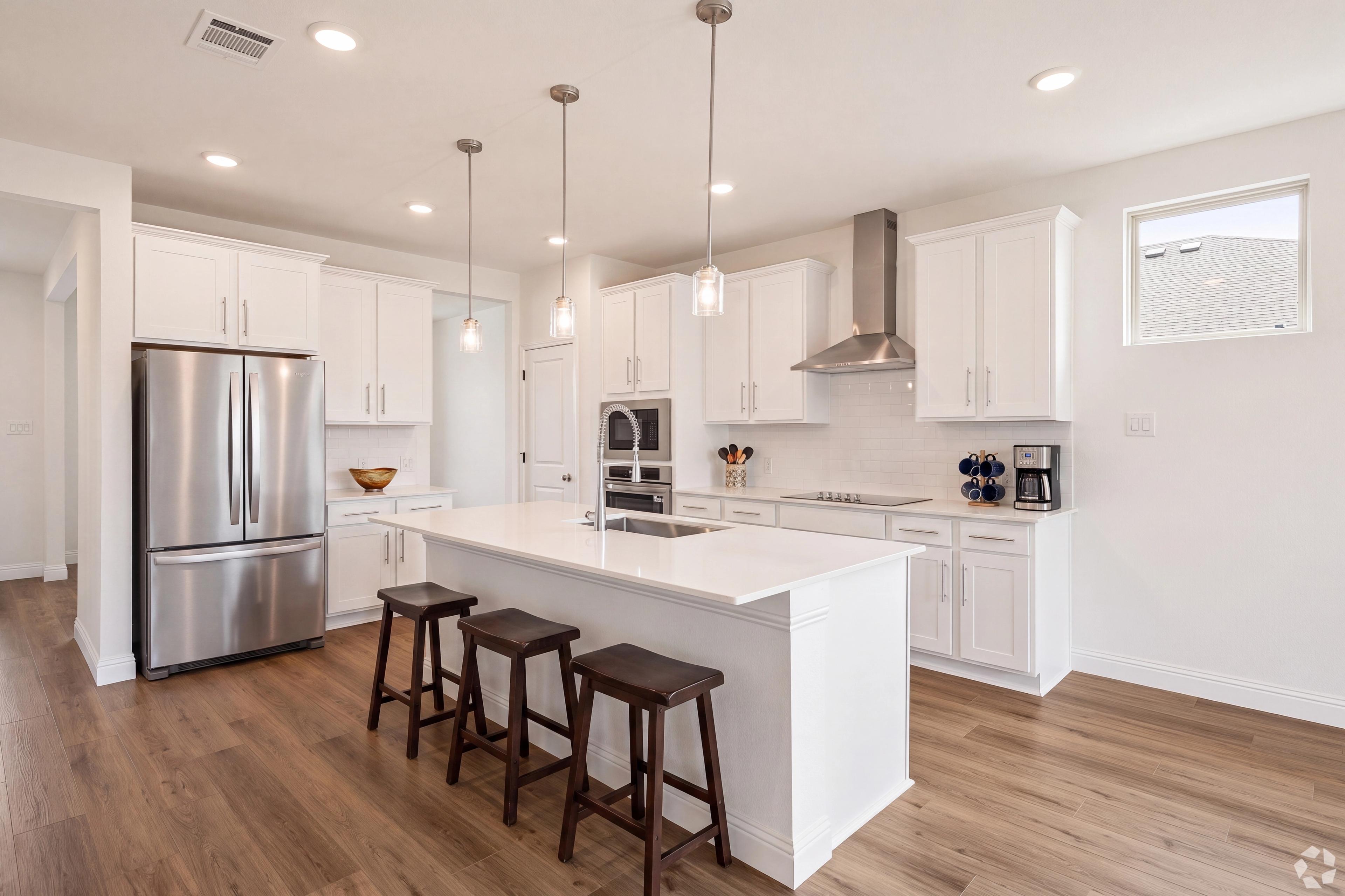 Open concept kitchen with white cabinets and stainless appliances at Mercer Meadows in Royse City, TX