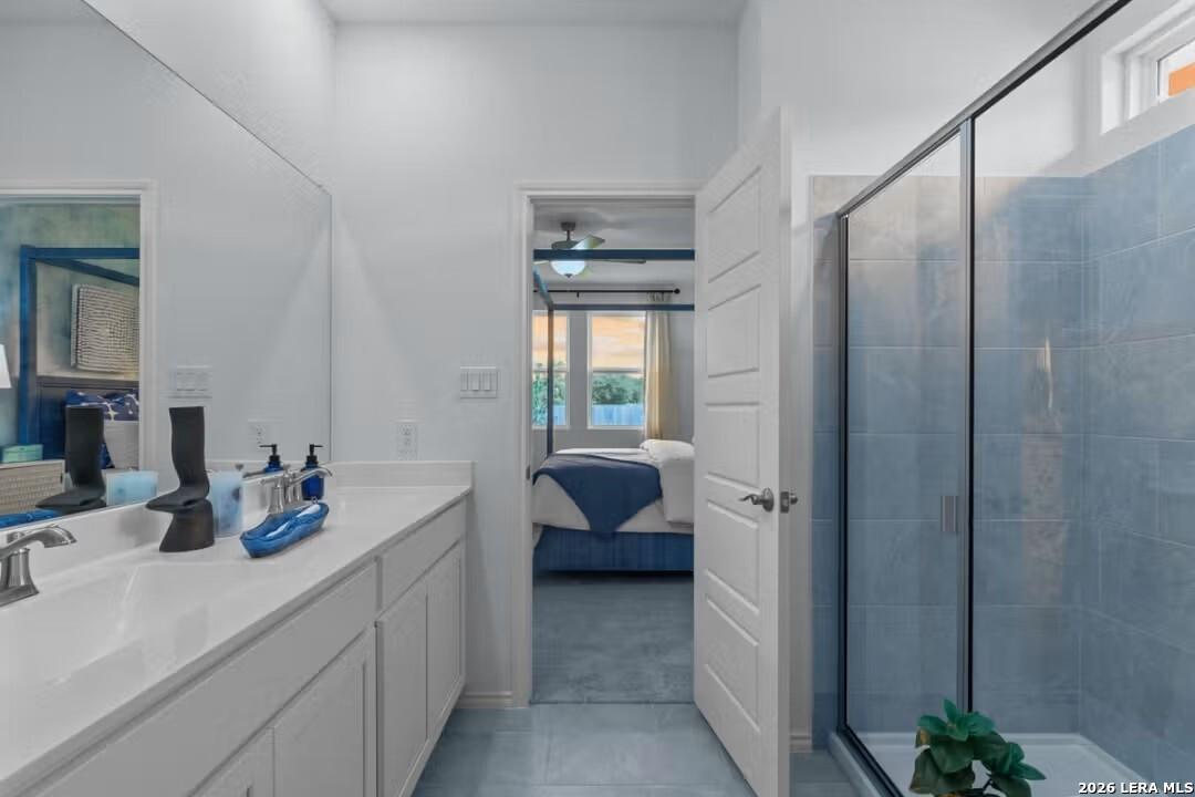 Modern master bath with double white vanity, blue tile walk-in shower, and open bedroom door in Davidson Homes The Daphne H, Seguin, Texas