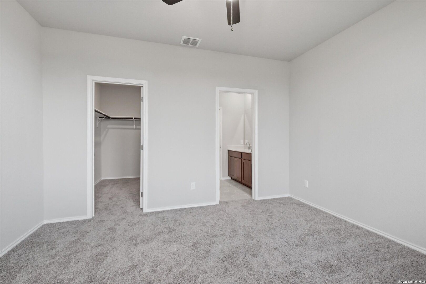 Master bedroom with ceiling fan, walk-in closet rod, and en-suite bathroom vanity in Davidson Homes The Frio B, San Antonio
