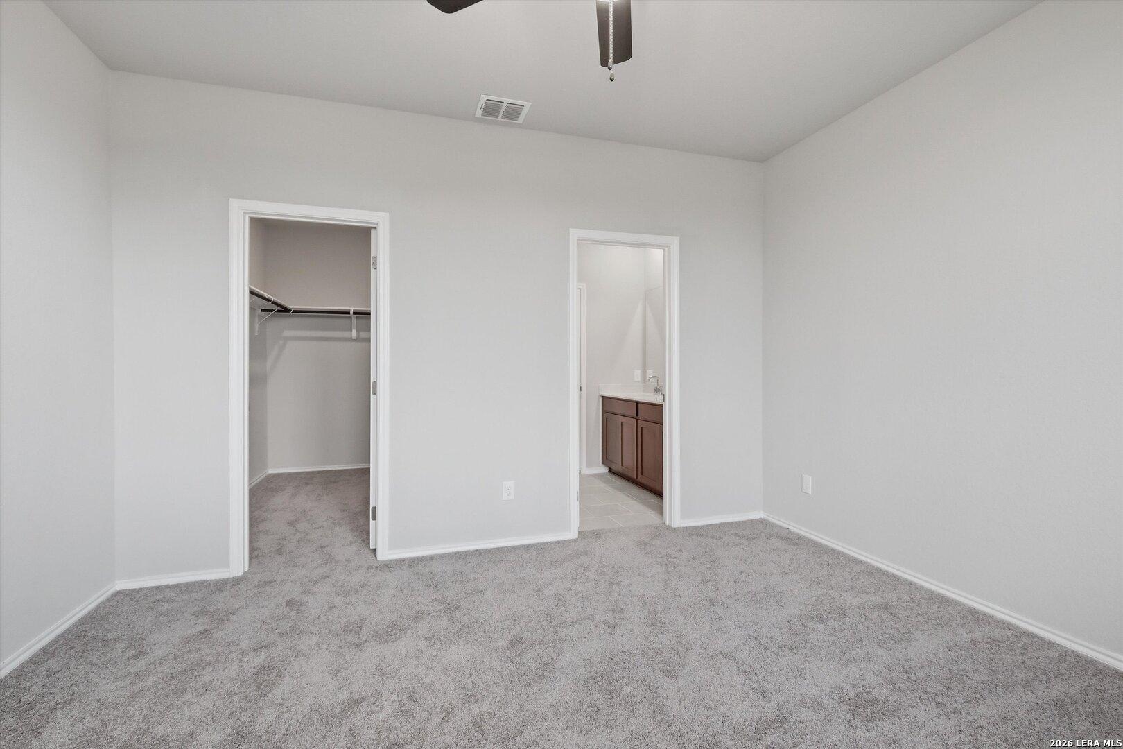 Master bedroom with ceiling fan, walk-in closet rod, and en-suite bathroom vanity in Davidson Homes The Frio B, San Antonio