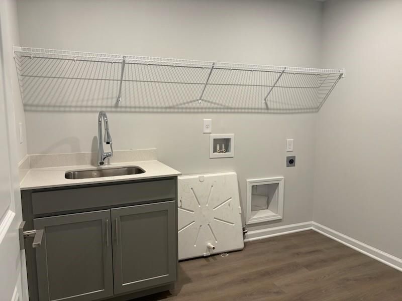 Functional laundry room with utility sink, gray cabinets, wire shelving in Davidson Homes Marion A, Winder, Georgia
