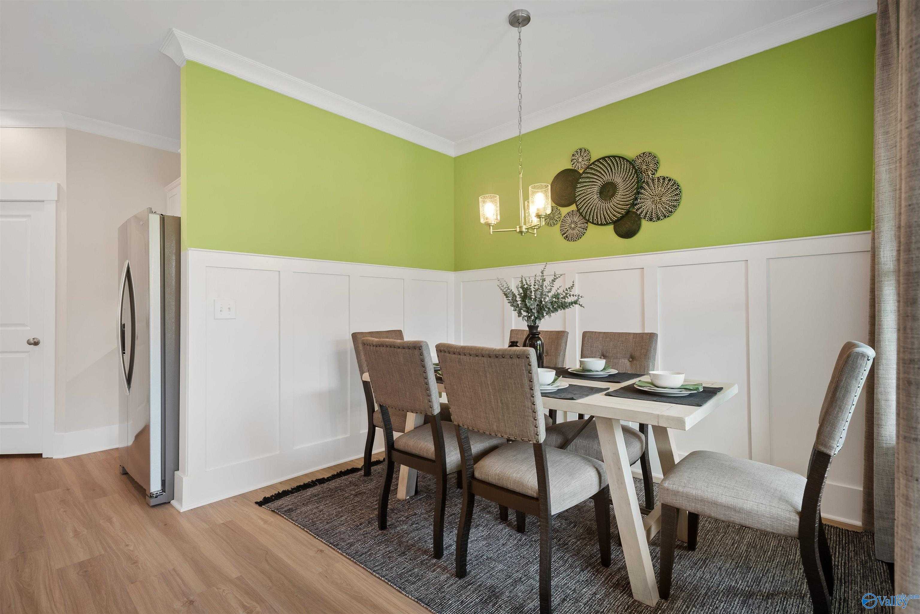 Modern dining room with green accent wall, shiplap details, wooden table, upholstered chairs in Davidson Homes The Daphne, Harvest AL