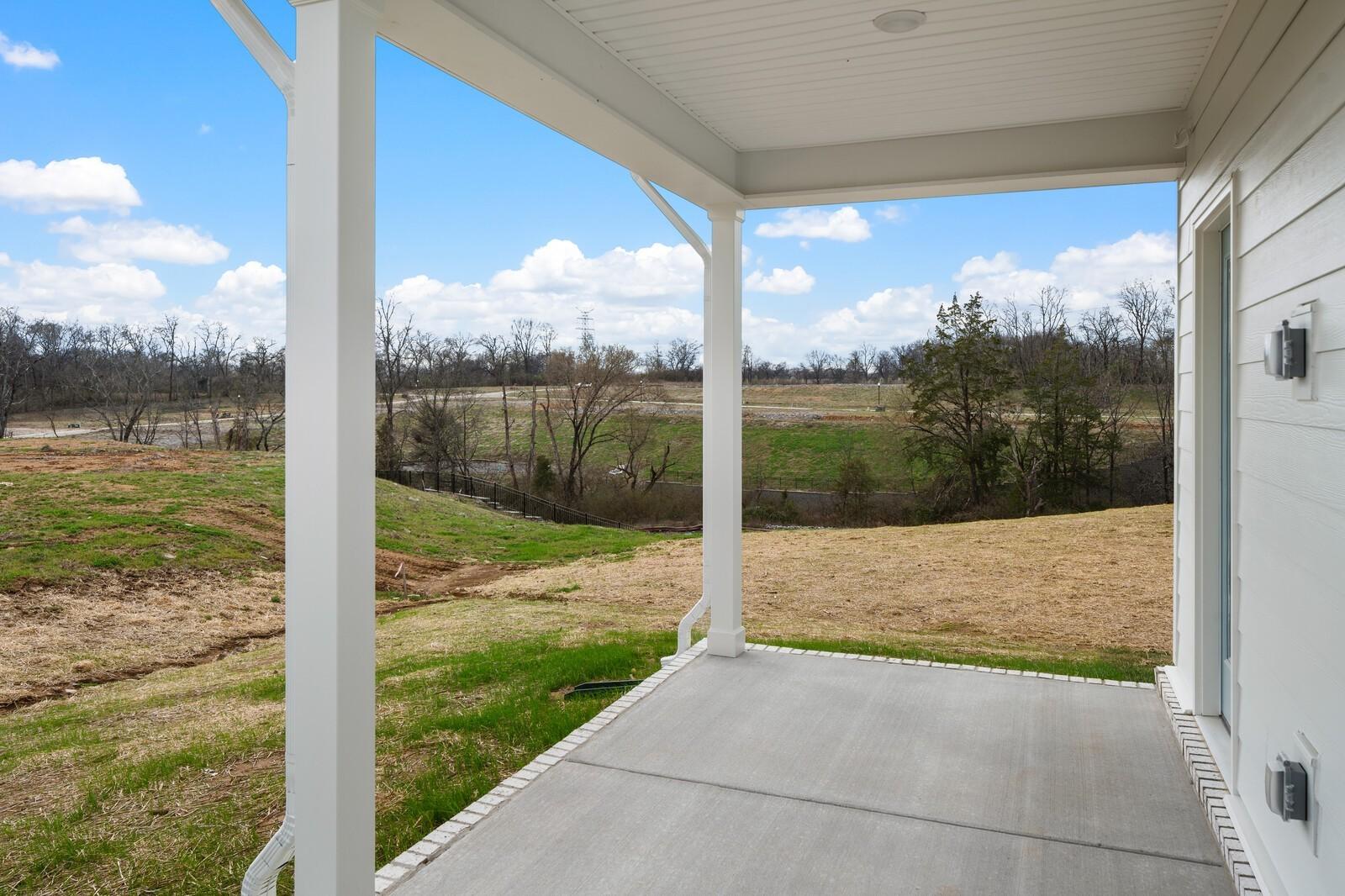 Covered back patio with concrete deck and white columns overlooking scenic fields and river in Davidson Homes Ridgeport, Gallatin, TN