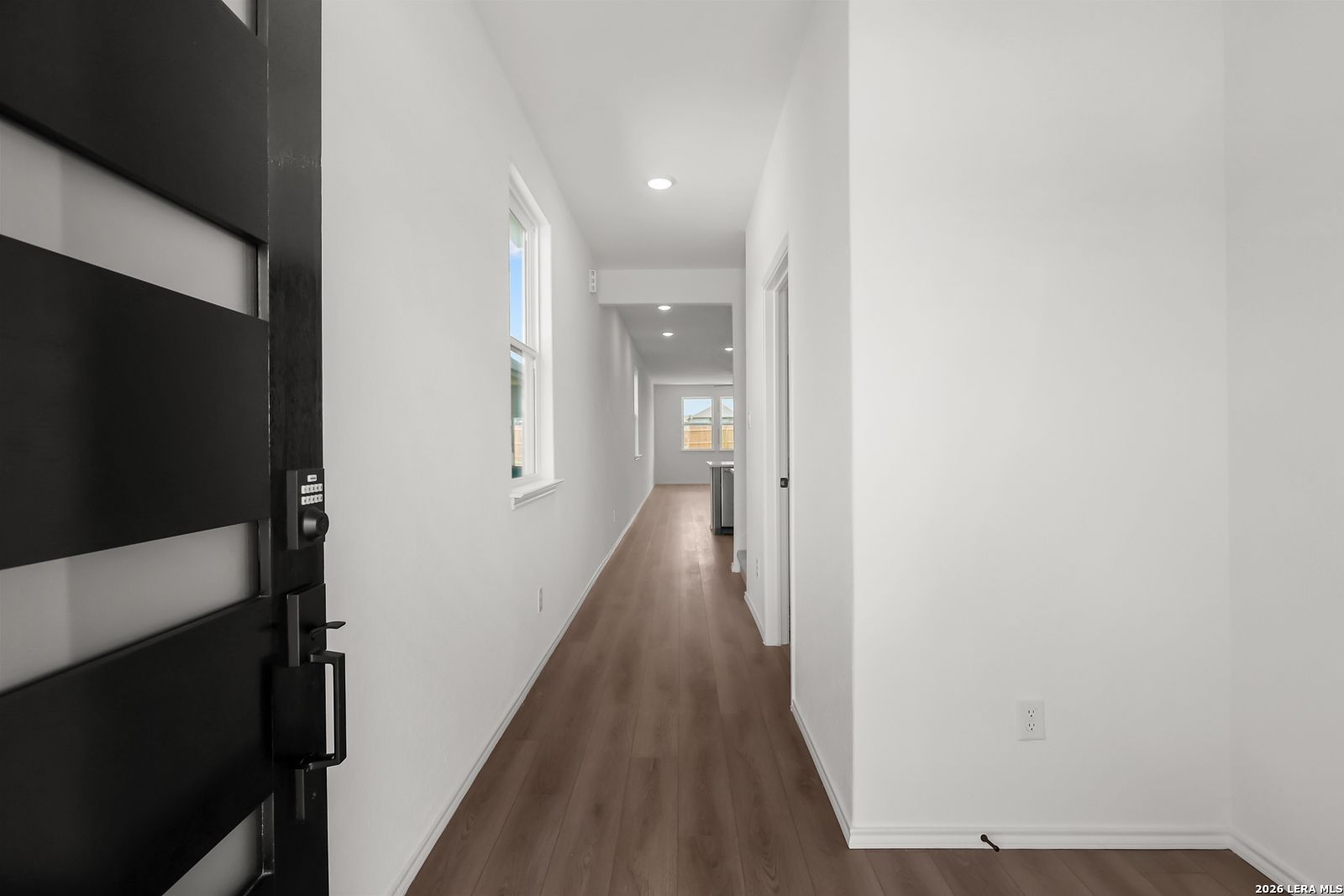 Entryway with black front door and keypad lock, wood-look flooring in Davidson Homes The Pinecrest F plan, Morgan Meadows, San Antonio