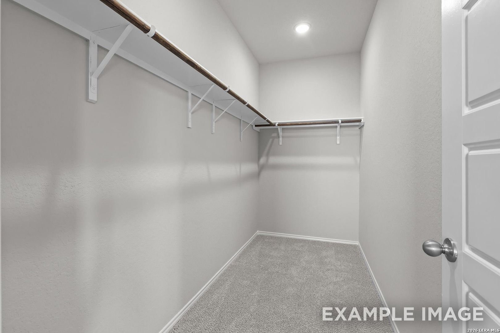 Spacious walk-in closet with wooden hanging rods and shelves in Davidson Homes The Colorado D, Agave, San Antonio, Texas