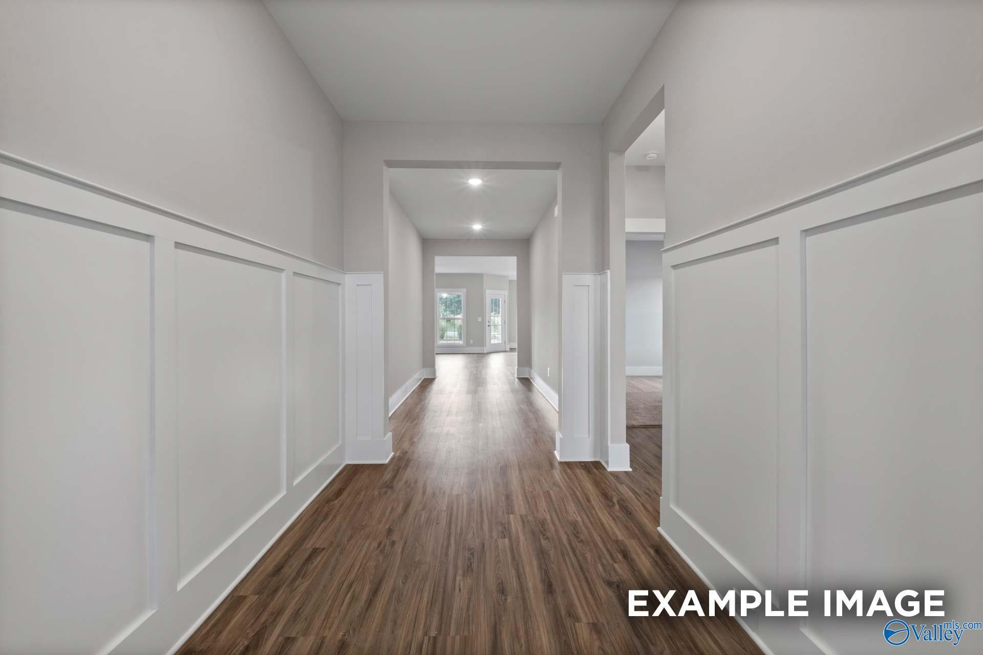 Spacious hallway with white wainscoting, hardwood floors, and recessed lights in Davidson Homes The Harrison, Cain Park, Hartselle