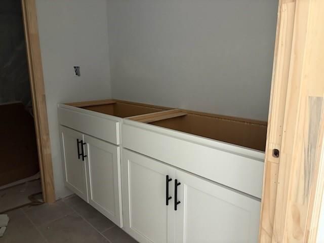 White shaker cabinets with black pulls and open framing in laundry room of Davidson Homes The Hickory B, Winder, GA