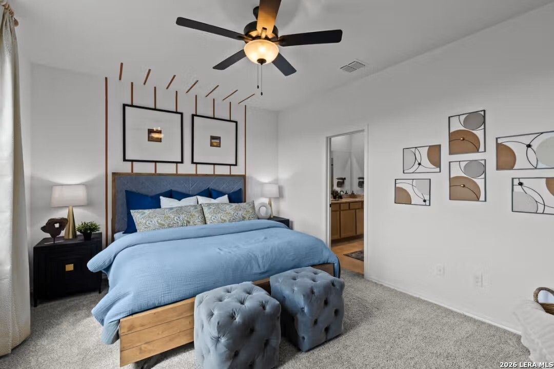 Elegant master bedroom with blue velvet headboard, king bed, ceiling fan, and abstract art in Davidson Homes The Douglas C, Converse, Texas