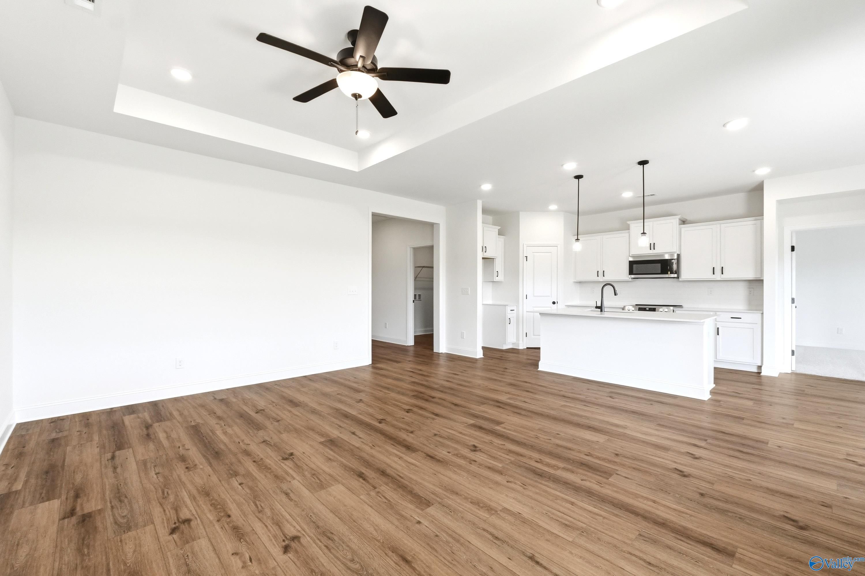 Open-concept living room and kitchen with tray ceiling in The Everett B floor plan, Clearview, Hazel Green, Alabama.