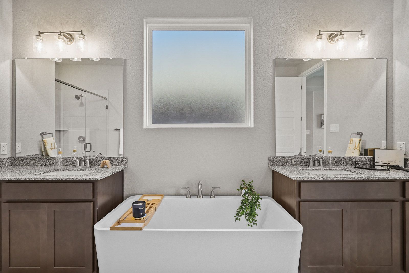 Modern master bathroom in The Jennings G featuring a soaking tub, dual granite vanities, and bright natural light.
