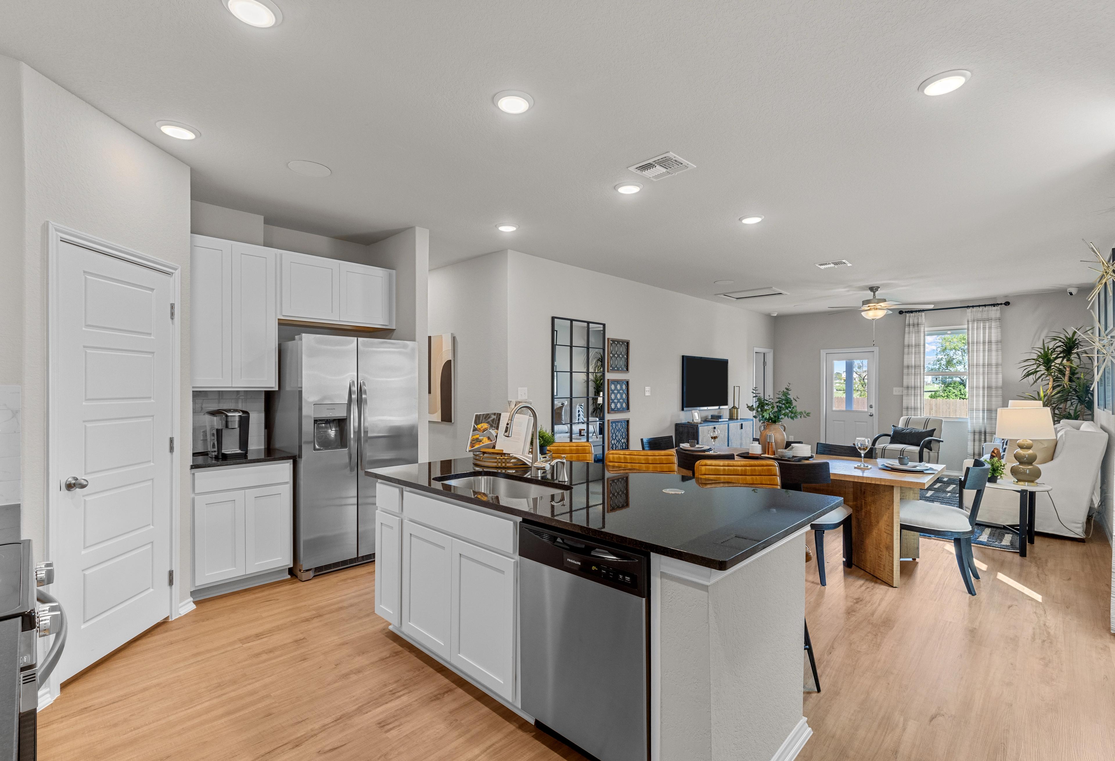 Gourmet kitchen in The Sabine A Davidson Homes design with white cabinets, black granite island, stainless appliances, and open dining area
