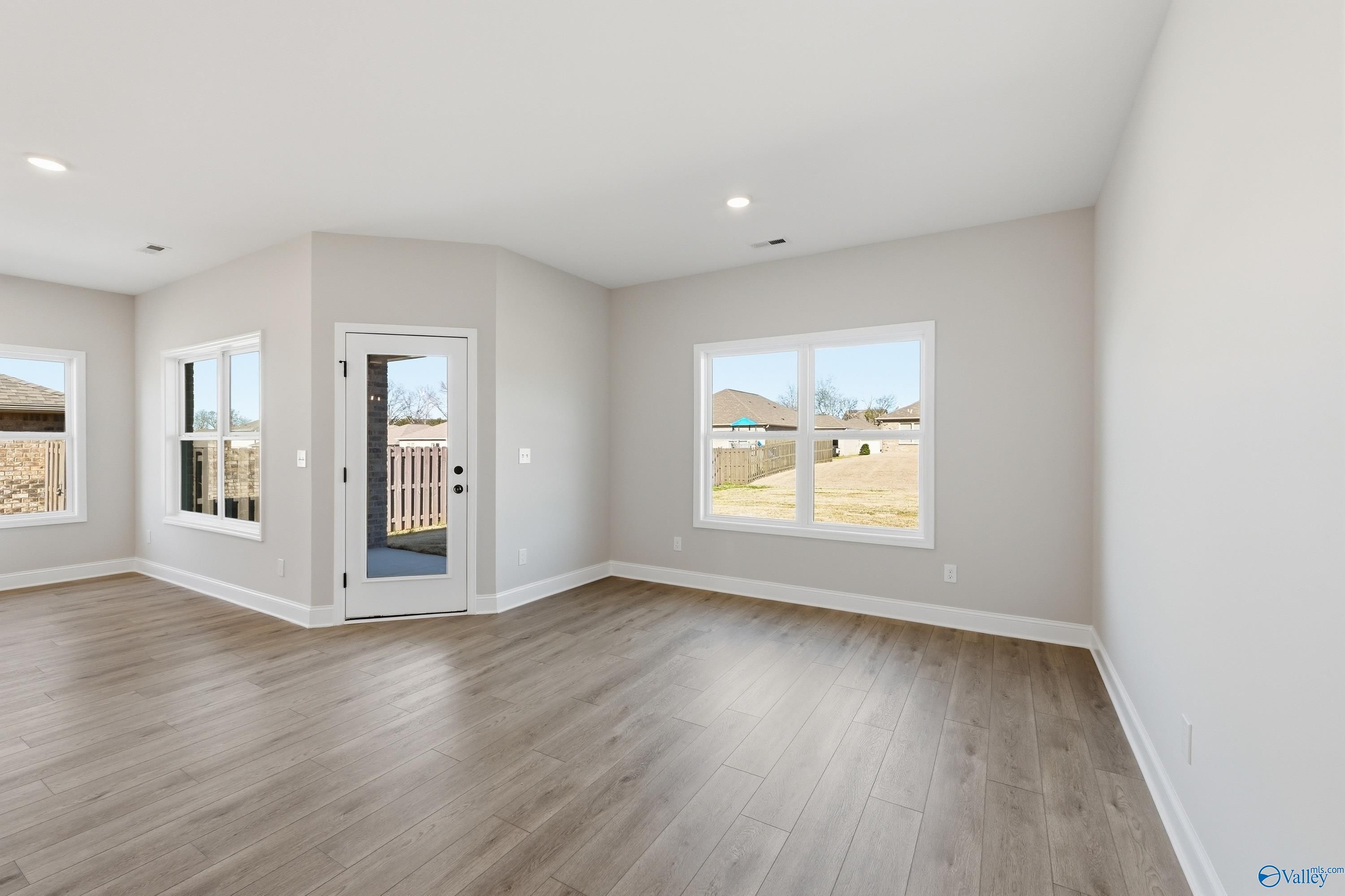 Bright living room with gray walls, hardwood floors, large windows, and sliding door to grassy backyard in Davidson Homes Franklin C, New Market AL