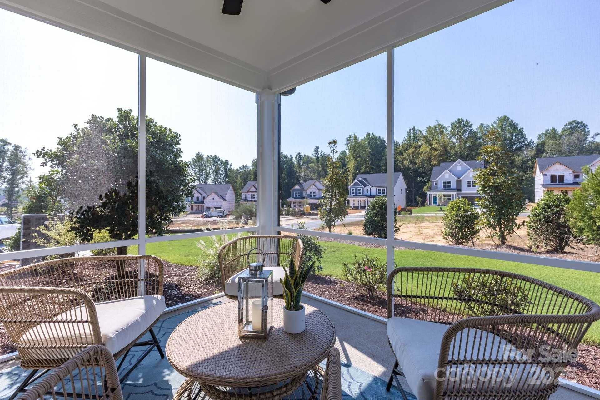 Screened porch with wicker chairs and table overlooking landscaped backyard in Davidson Homes The Hickory E II, Enclave at Belmont, NC