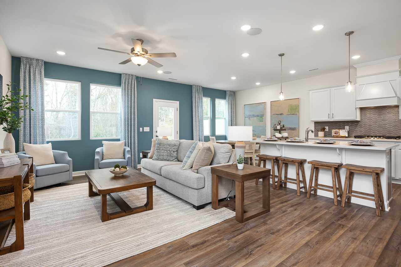 Open-concept living room and kitchen at Gregory Village Townhomes in Lillington NC with gray sofa, wood floors, and bar island