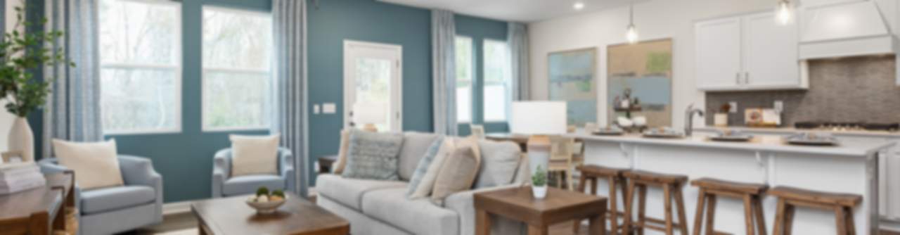 Modern open-concept living room and kitchen in new Wylie home, gray sofa, island bar, hardwood floors