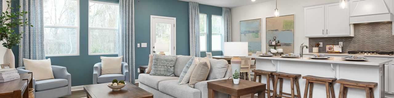 Modern open-concept living room and kitchen in new Wylie home, gray sofa, island bar, hardwood floors