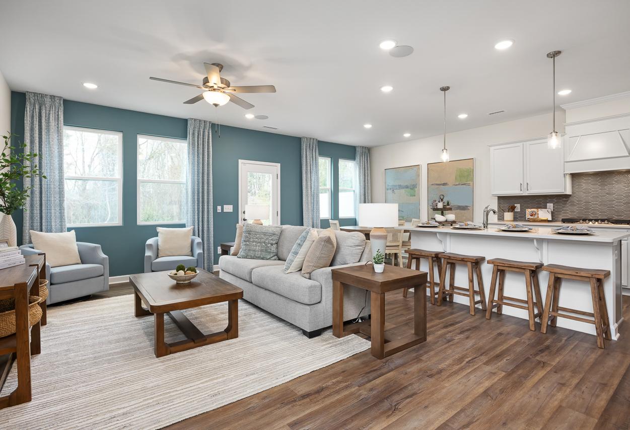 Open-concept living room and kitchen in The Wake floor plan featuring a spacious island, modern decor, and teal accent wall.