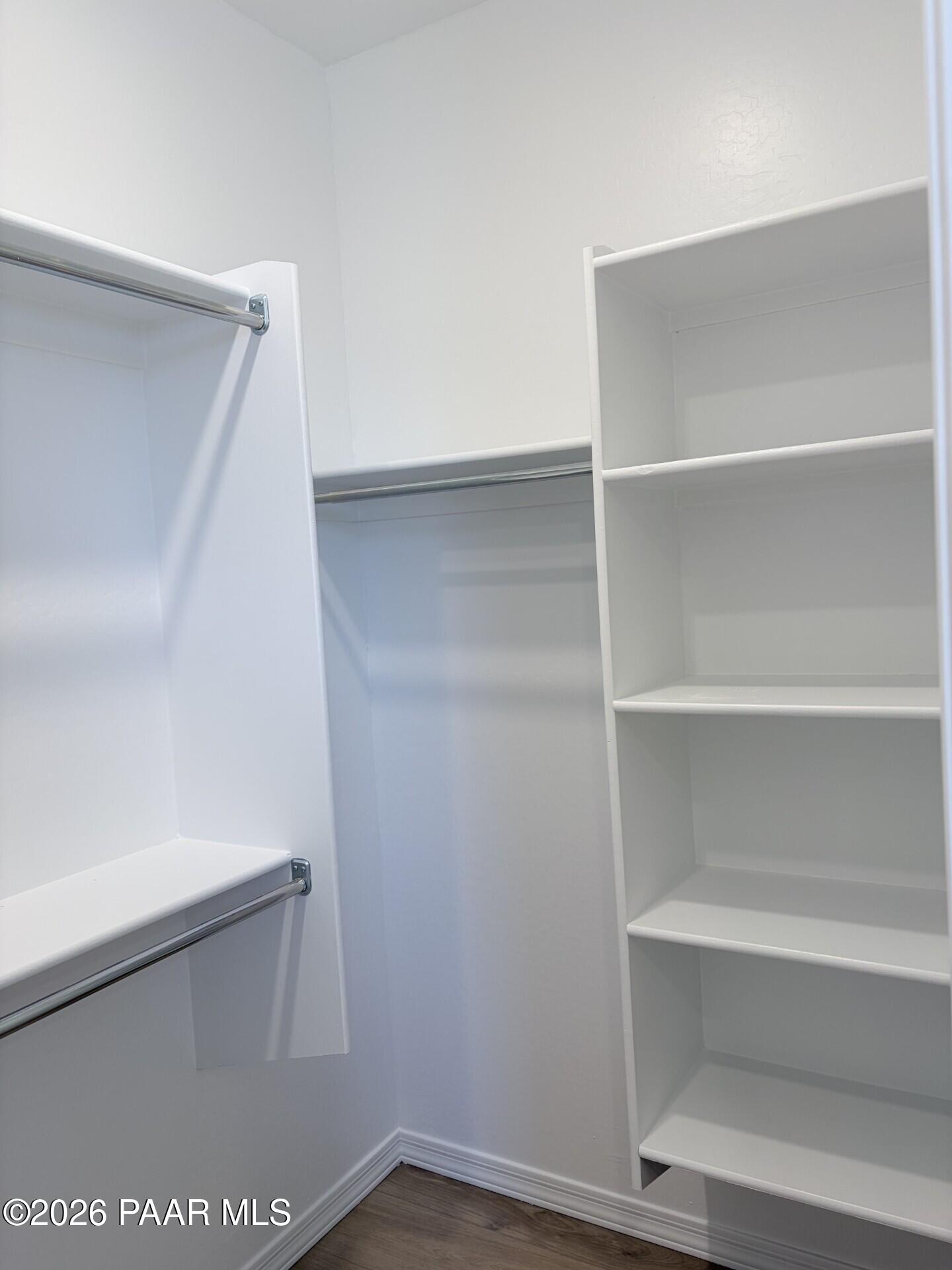 Walk-in closet with custom white shelving and hanging rods in The Frontier A home at North Ridge, Pronghorn Ranch.