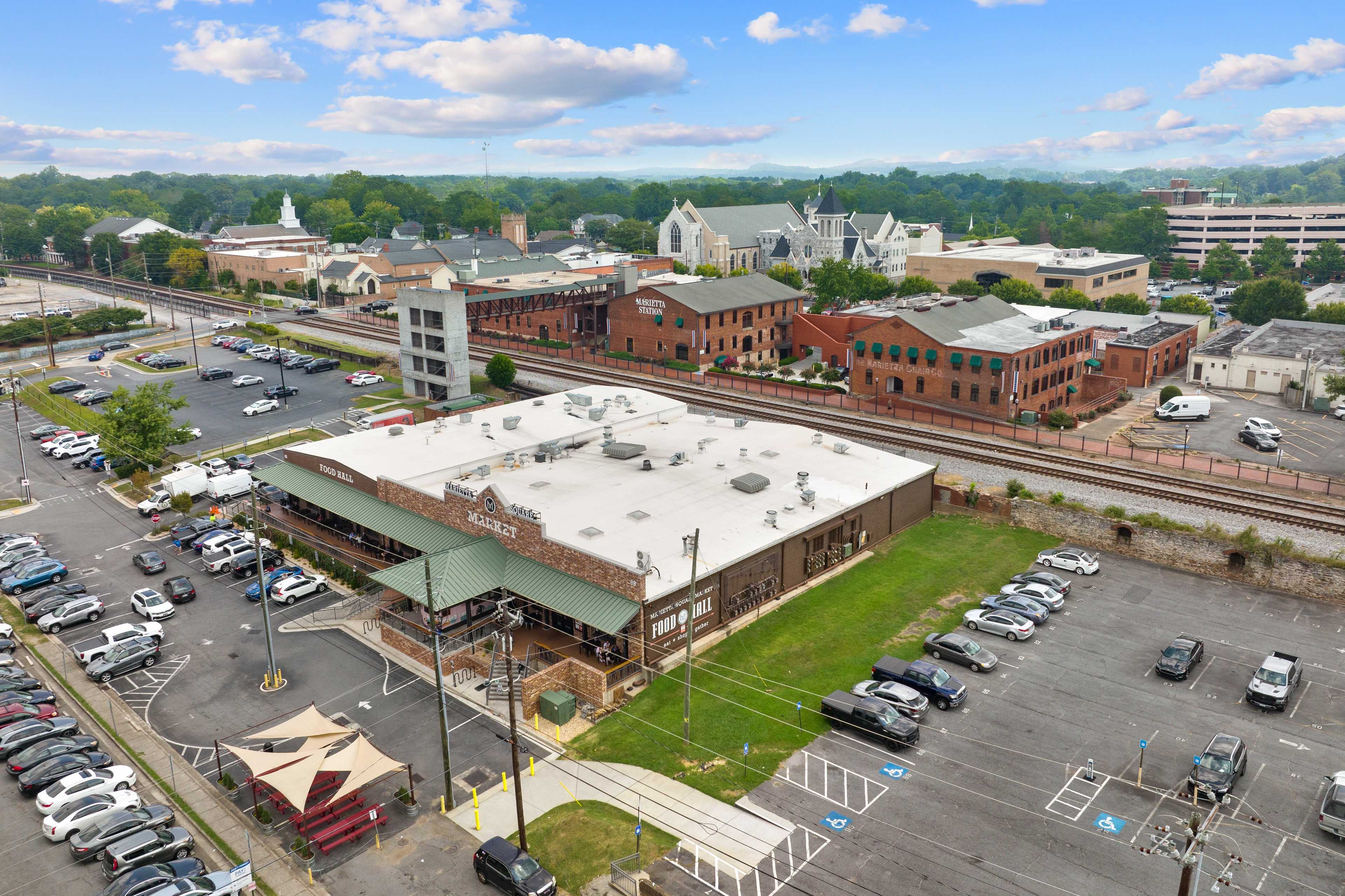 Aerial view of Rosehill Townhomes neighborhood in Marietta Georgia with brick buildings, railroad tracks, parking lots, and church steeple