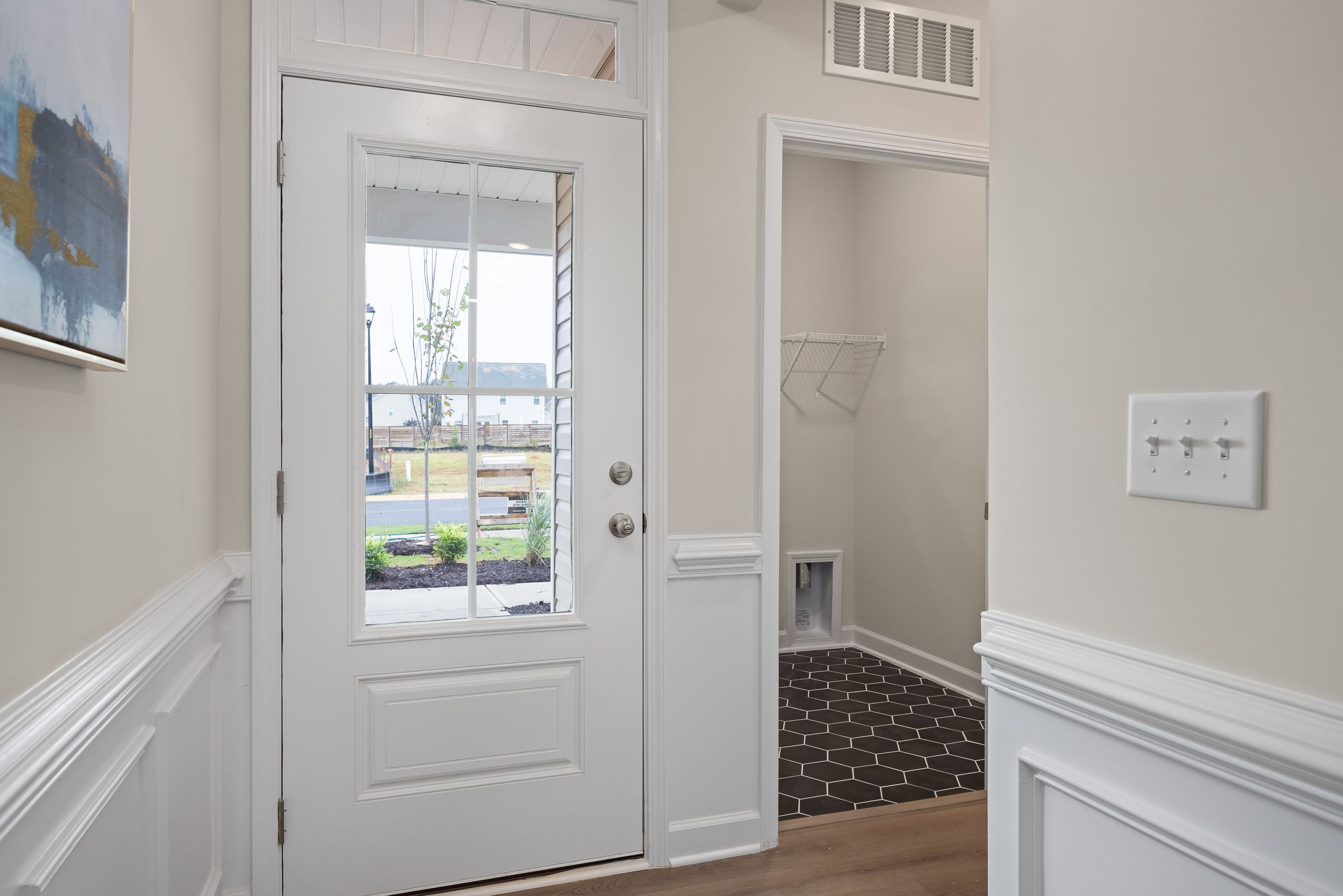 Bright entryway with white front door and wainscoting at Gregory Village in Lillington, NC by Davidson Homes.