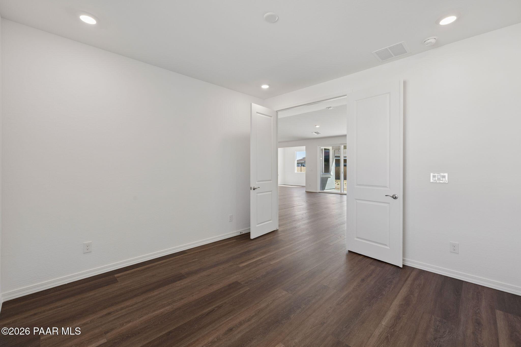 Bright bedroom with open doors to spacious living area, hardwood floors, and natural light in Davidson Homes The Monarch A, Prescott AZ