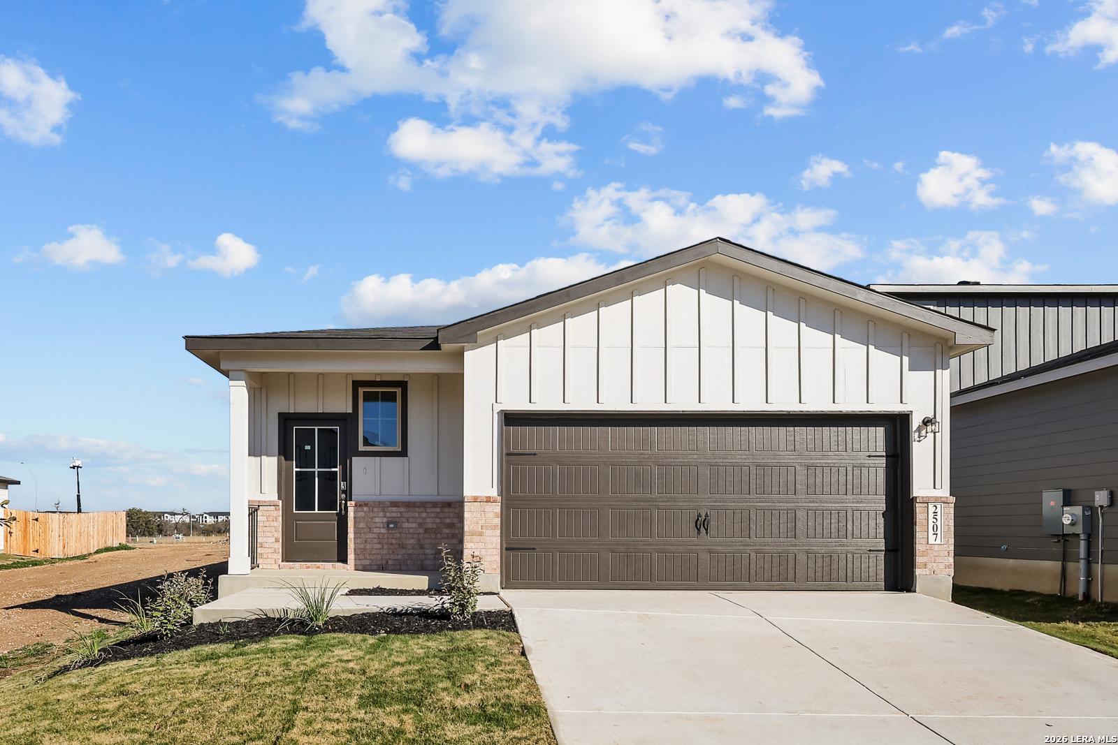 Modern 3-bed single-story home with white shiplap siding, brown 2-car garage, and landscaped front yard in San Antonio, Texas