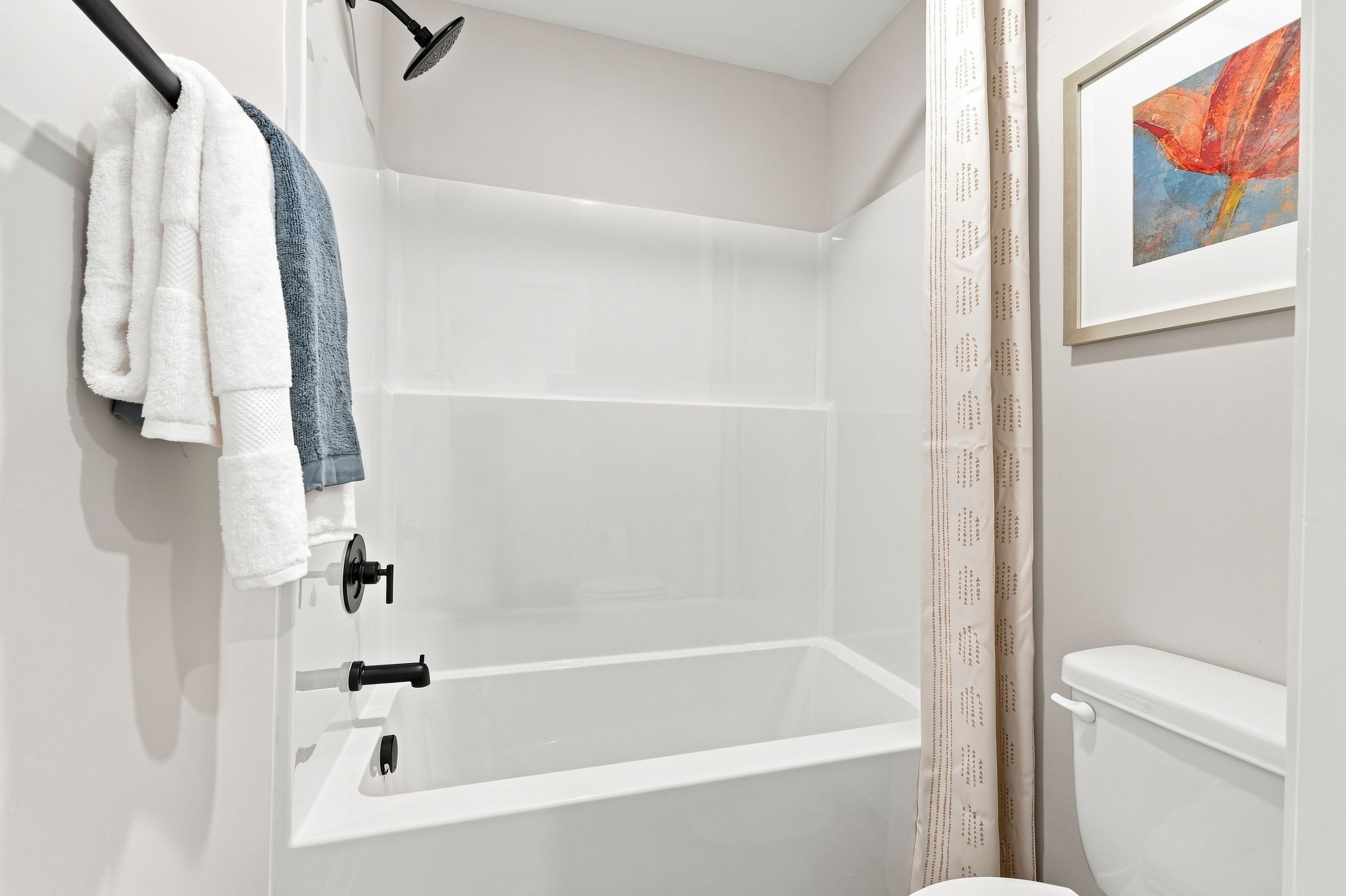 White bathtub with matte black shower fixtures and towels at Bailey Park by Davidson Homes in Fayetteville, Tennessee
