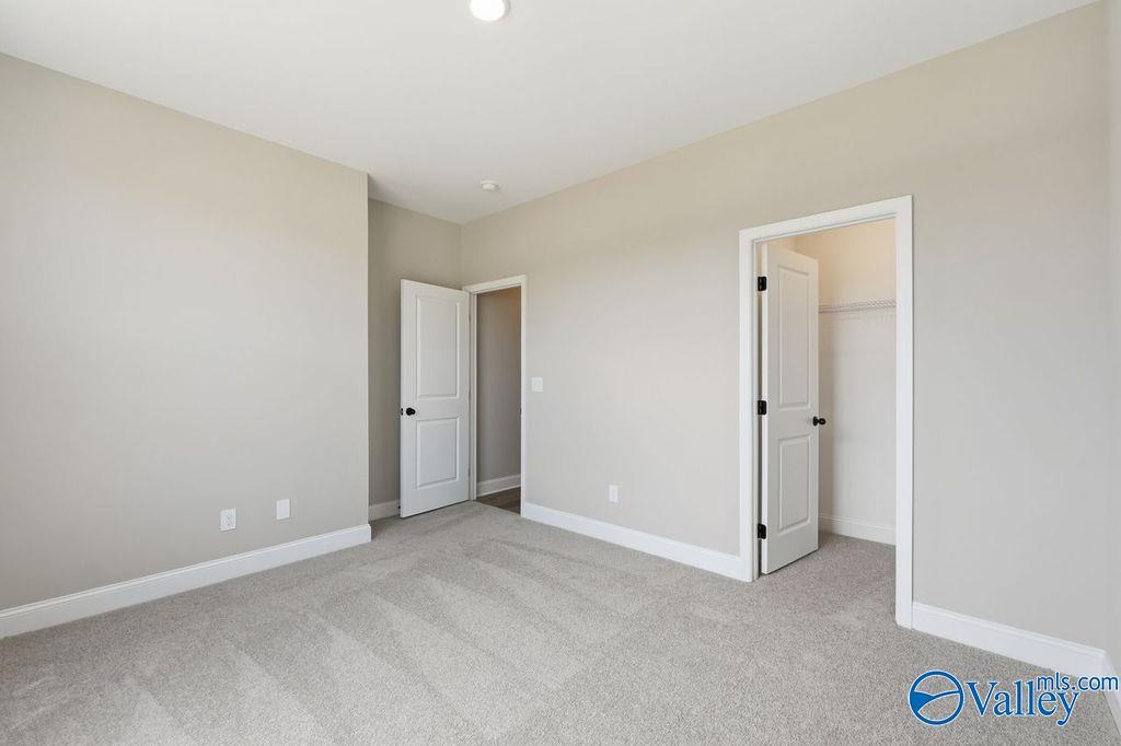 Spacious carpeted bedroom with walk-in closet in The Rockford floor plan by Davidson Homes in Cain Park, Hartselle, AL.