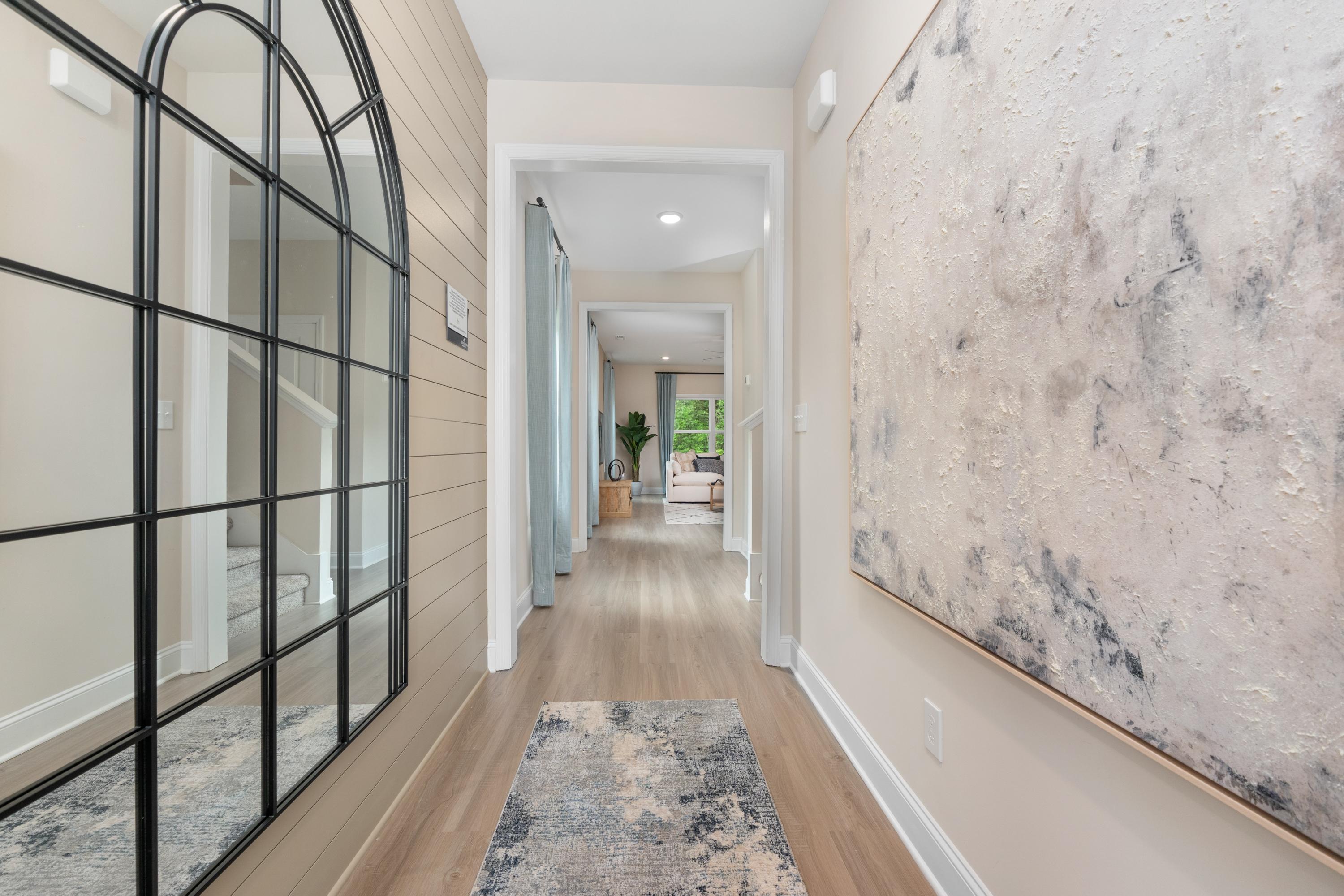 Spacious hallway with arched black mirror, hardwood floors, abstract art at Pavilion in Huntsville AL