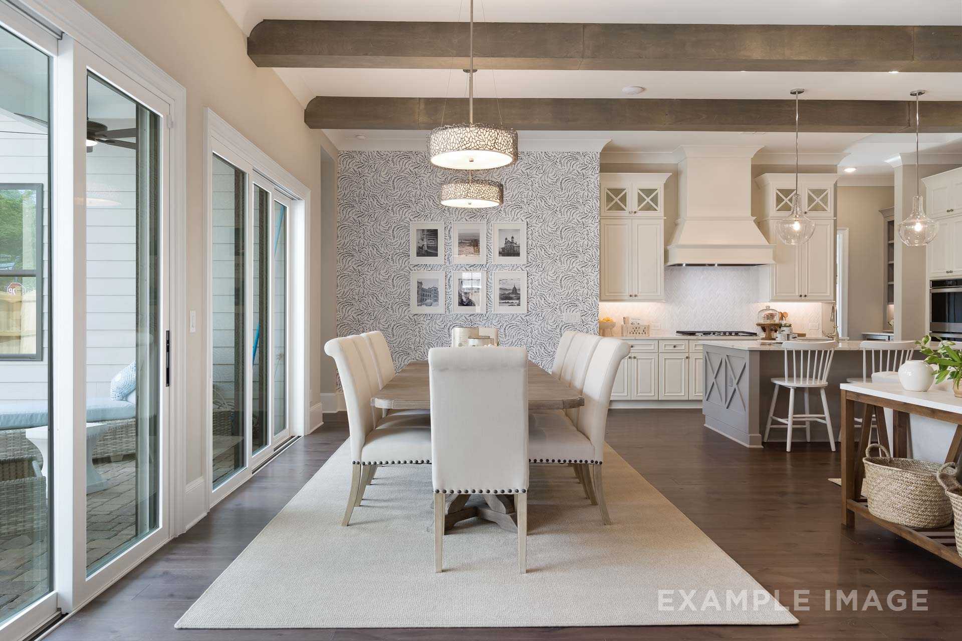 Spacious open-concept dining area in The Seaside home with farmhouse table, shiplap walls, wood beam ceiling, and adjacent white kitchen island