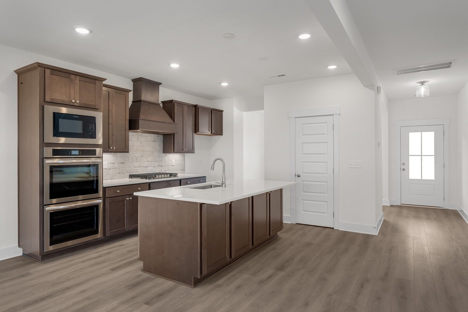 Modern kitchen with shaker cabinets, stainless double oven, white island sink, and hardwood floors in Davidson Homes Willow C, Gallatin, TN