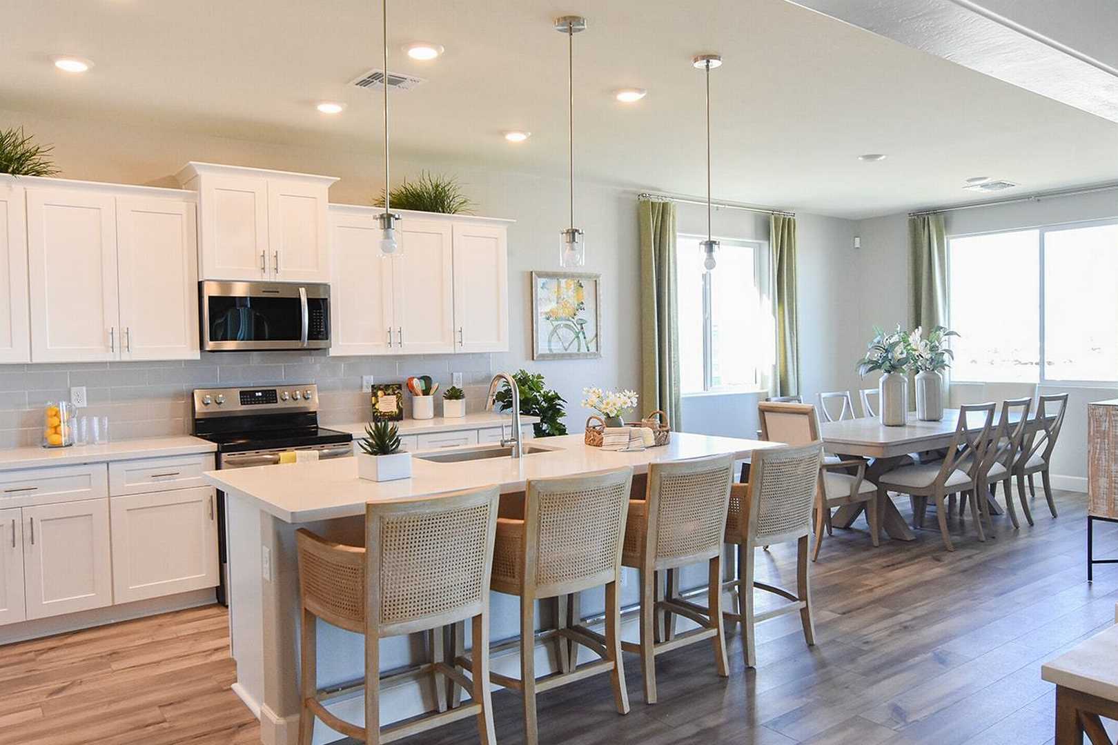 Spacious open-concept kitchen in The Summit B with white cabinetry, large island, wicker stools, and adjacent dining area