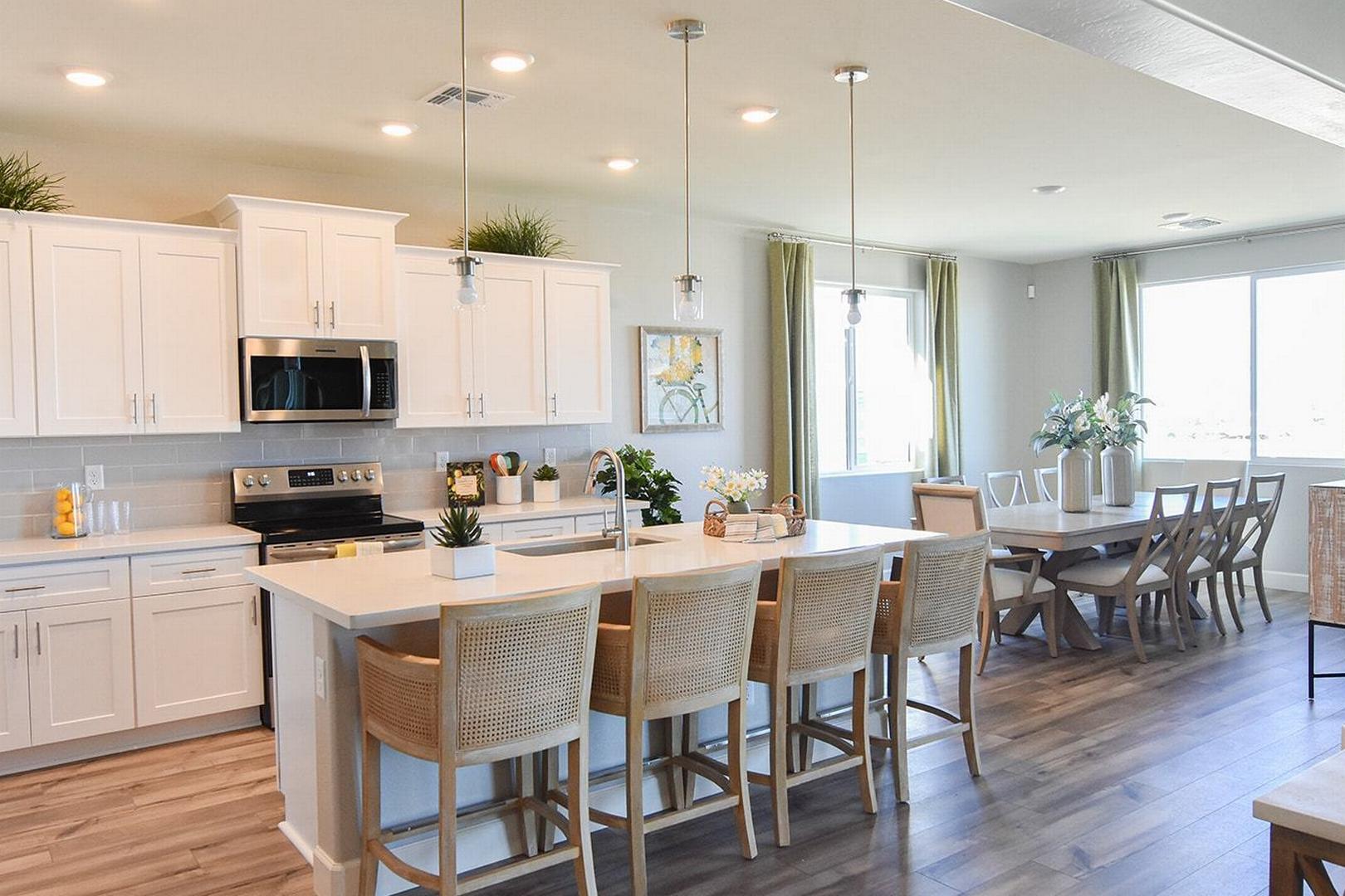 Spacious open-concept kitchen in The Summit E with white cabinetry, large island, pendant lights, and dining nook