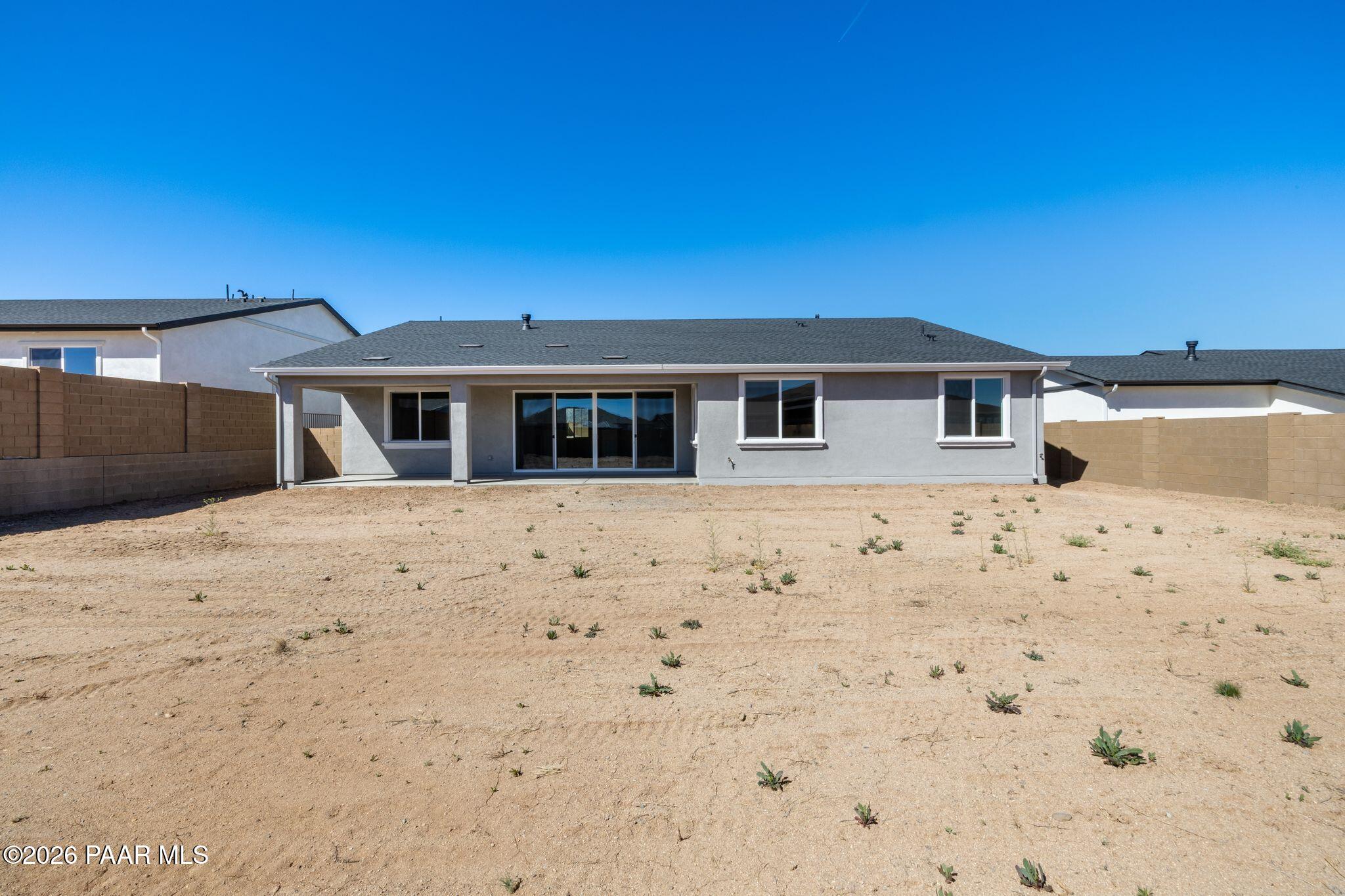 Rear view of Davidson Homes The Monarch A single-story home with sliding glass doors, covered patio, and fenced desert yard in Westwood, Prescott, Arizona