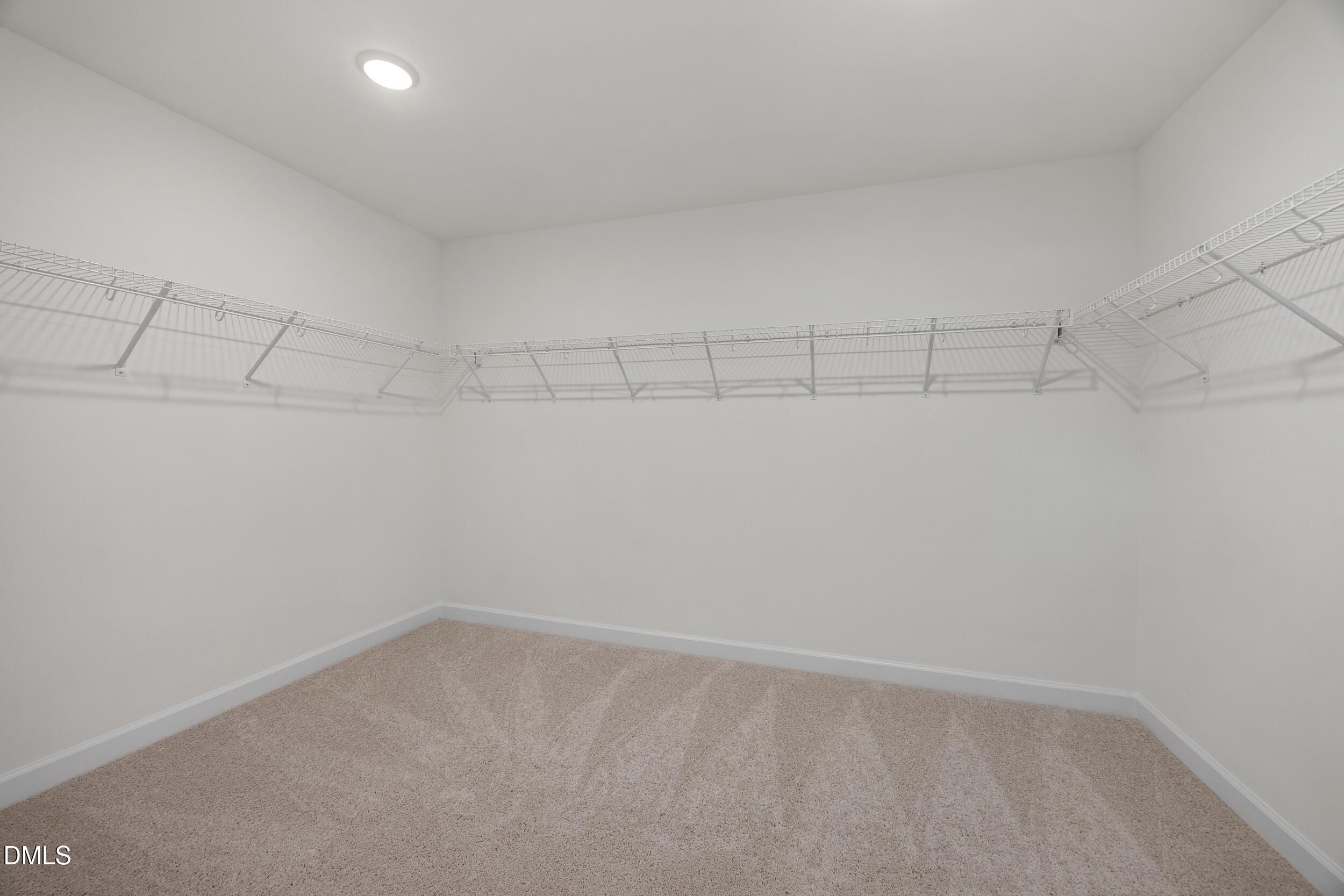 Spacious walk-in closet with white wire shelving and beige carpet in Davidson Homes The Preston C, Lillington, NC