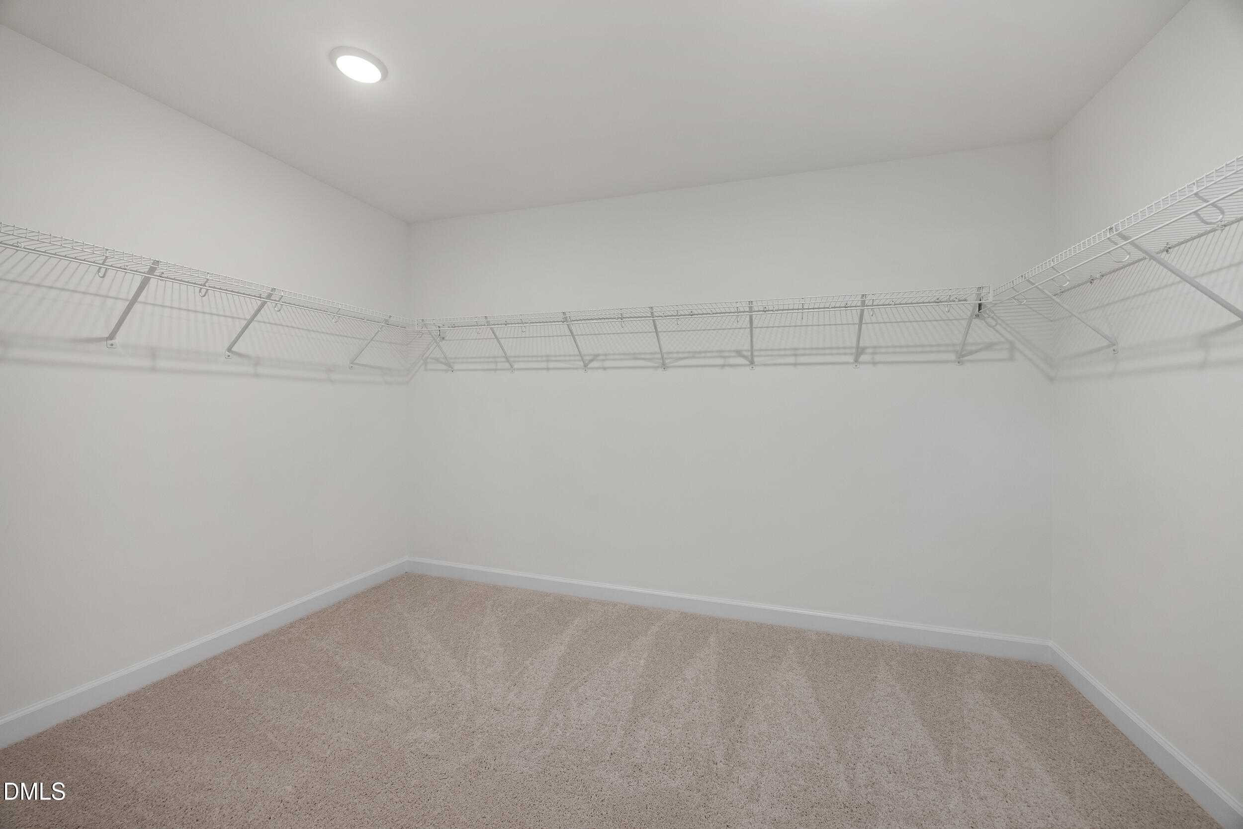 Spacious walk-in closet with white wire shelving and beige carpet in Davidson Homes The Preston C, Lillington, NC