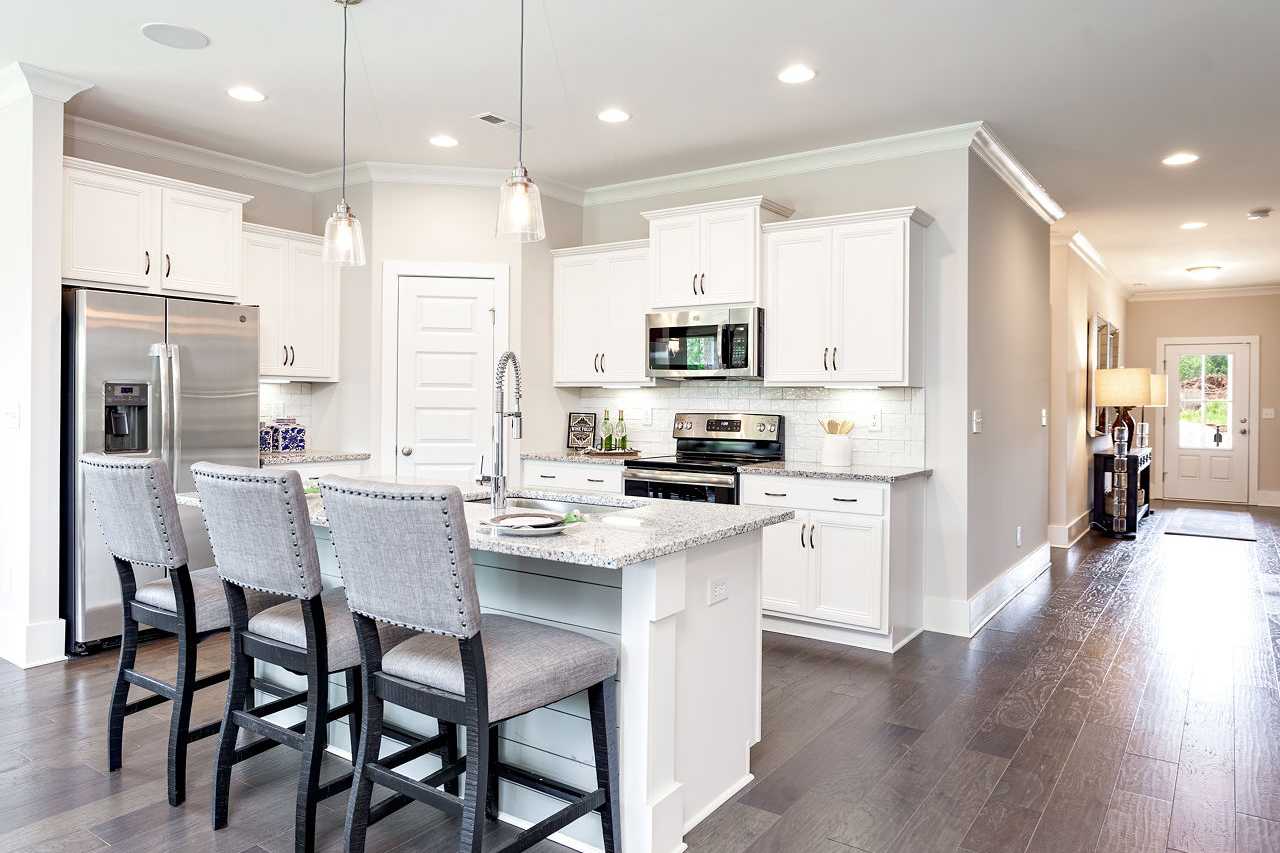 Spacious modern kitchen at Williams Pointe in Huntsville AL with white shaker cabinets, quartz island, stainless appliances and bar stools