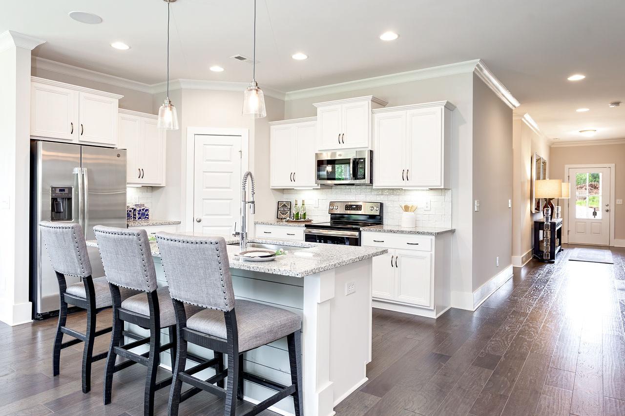 Spacious modern kitchen at Williams Pointe in Huntsville AL with white shaker cabinets, quartz island, stainless appliances and bar stools