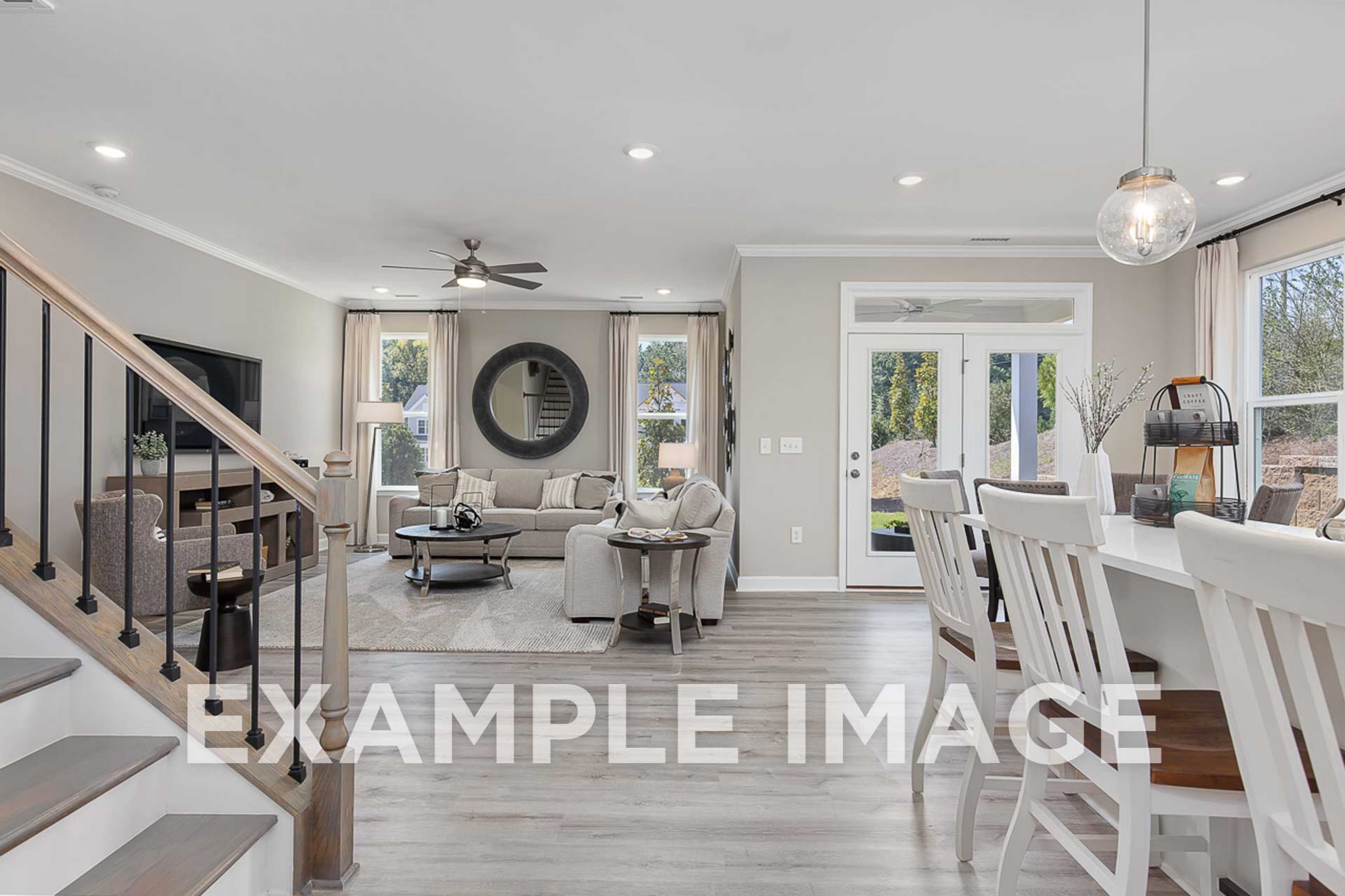 Spacious open-concept living and dining area in The Ash D home design featuring modern kitchen island, staircase, and large windows