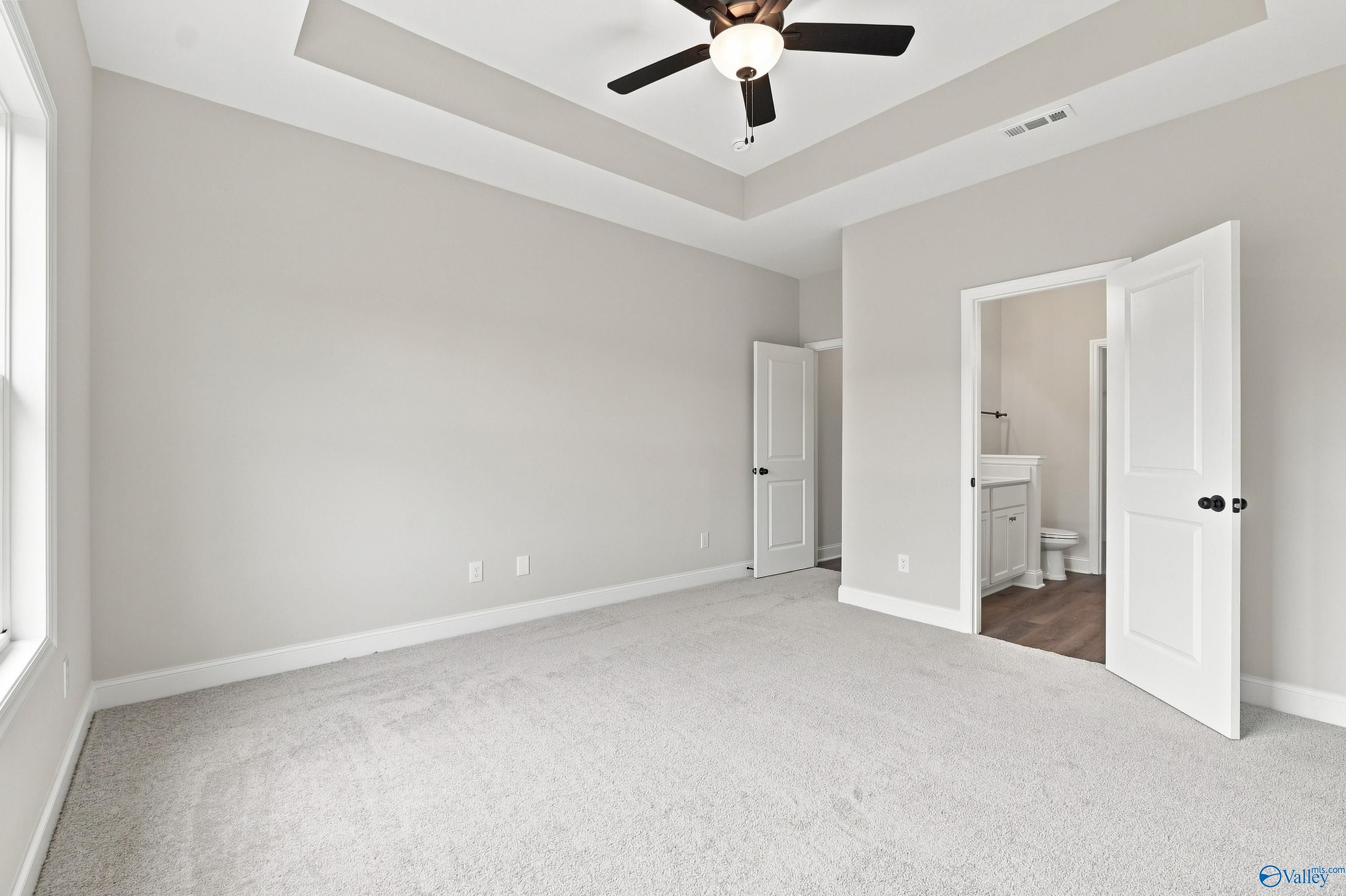 Spacious bedroom with tray ceiling and en-suite bathroom in The Asheville E floor plan by Davidson Homes in Forest Glen.