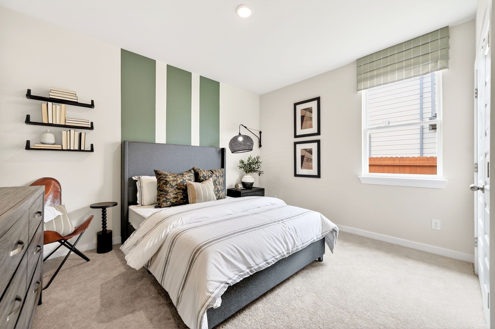 Modern bedroom with green accent wall in The Laurel M floor plan at Parks at Foster Crossing, Anna, Texas.