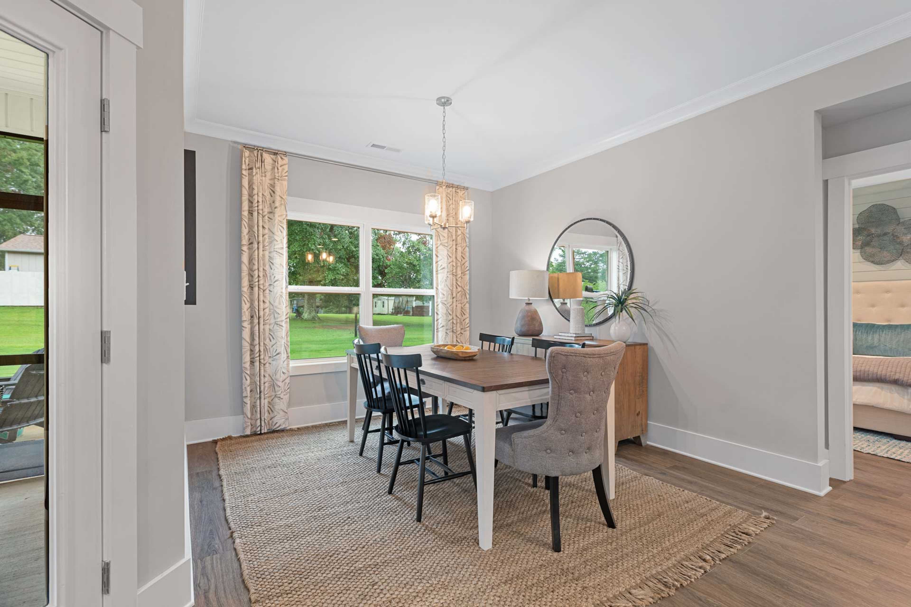 Dining room at Monteagle Cove in Owens Cross Roads AL by Davidson Homes featuring wooden table, black chairs, large windows overlooking lawn