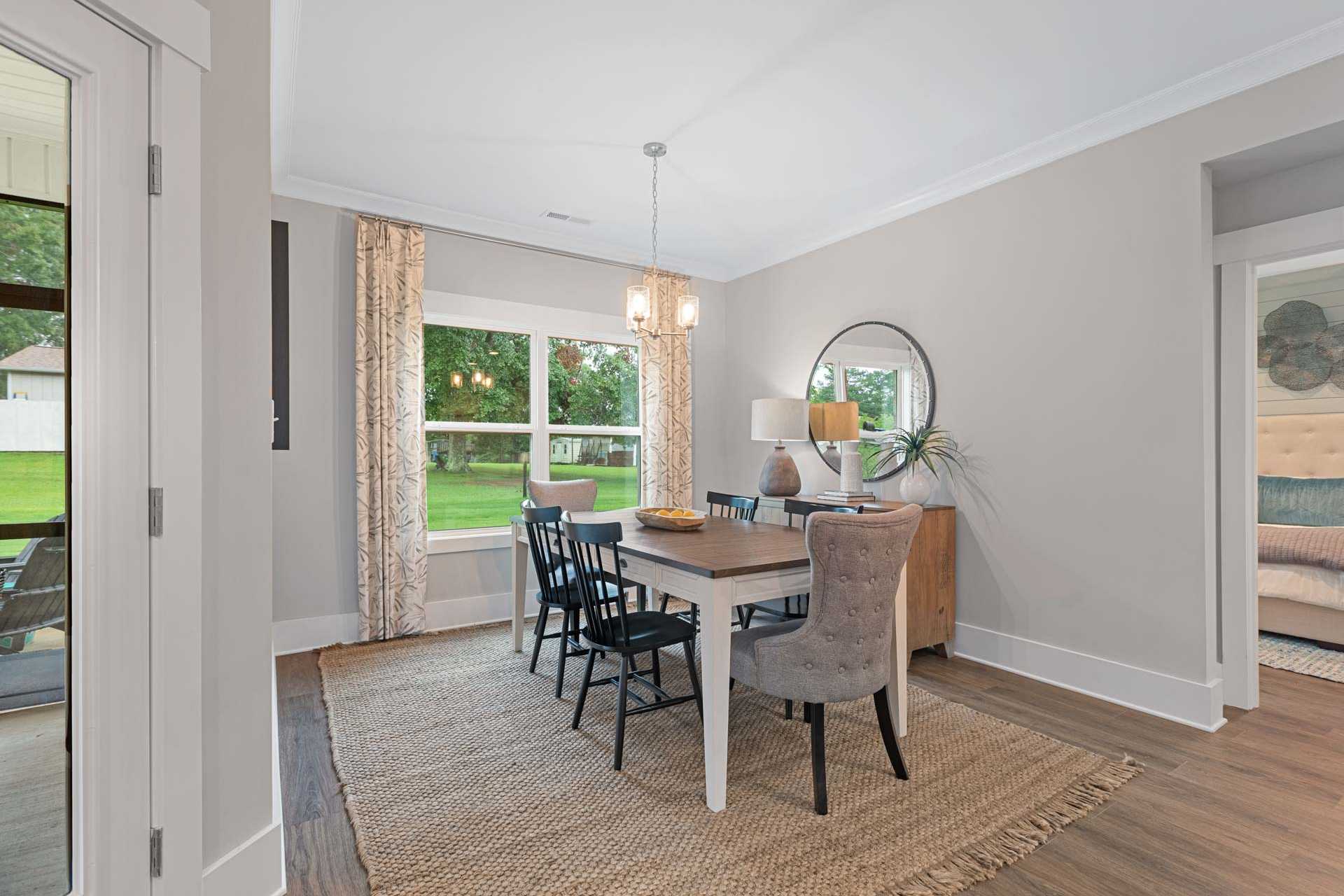 Dining room at Monteagle Cove in Owens Cross Roads AL by Davidson Homes featuring wooden table, black chairs, large windows overlooking lawn