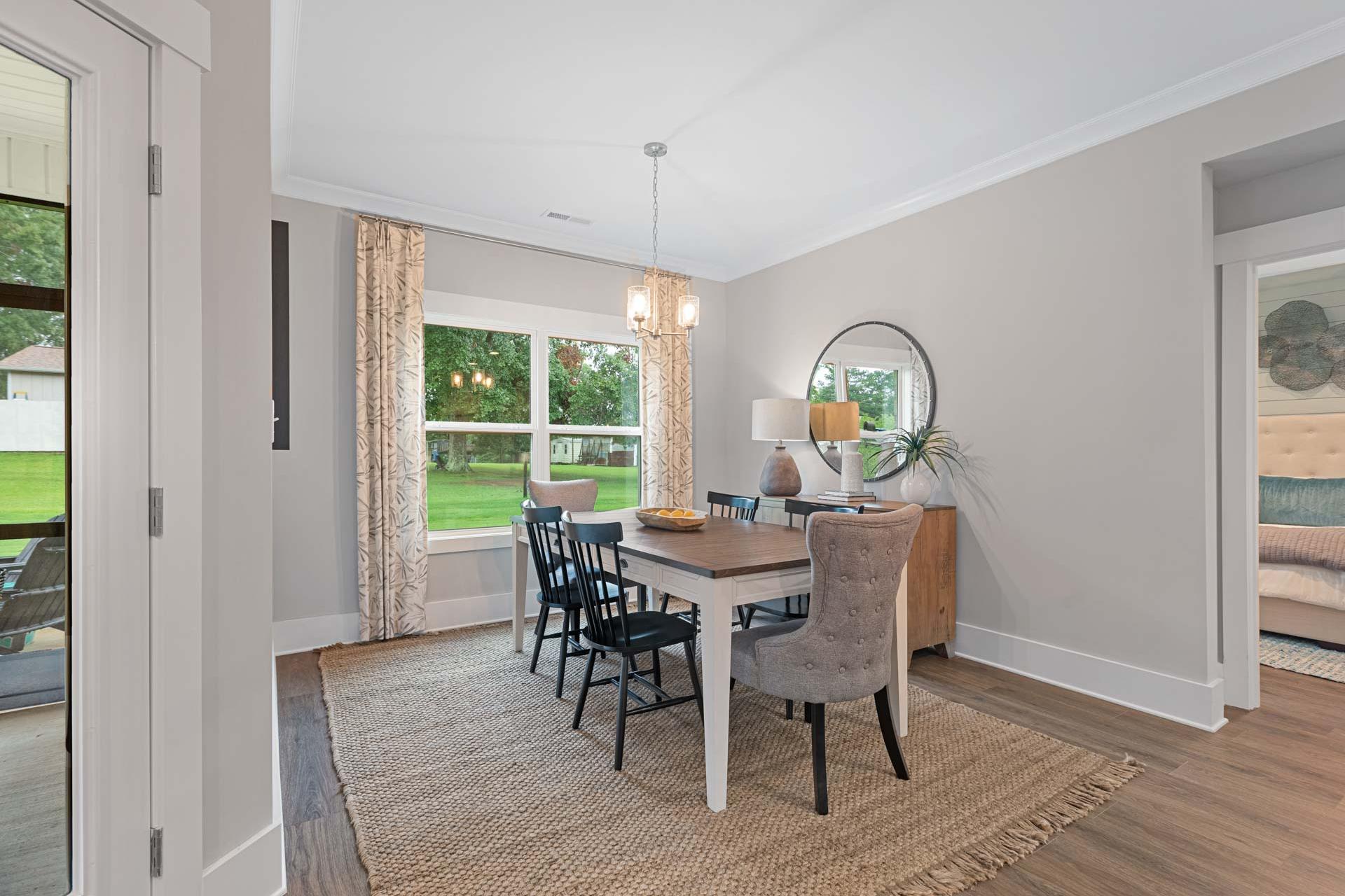 Dining room at Monteagle Cove in Owens Cross Roads AL by Davidson Homes featuring wooden table, black chairs, large windows overlooking lawn