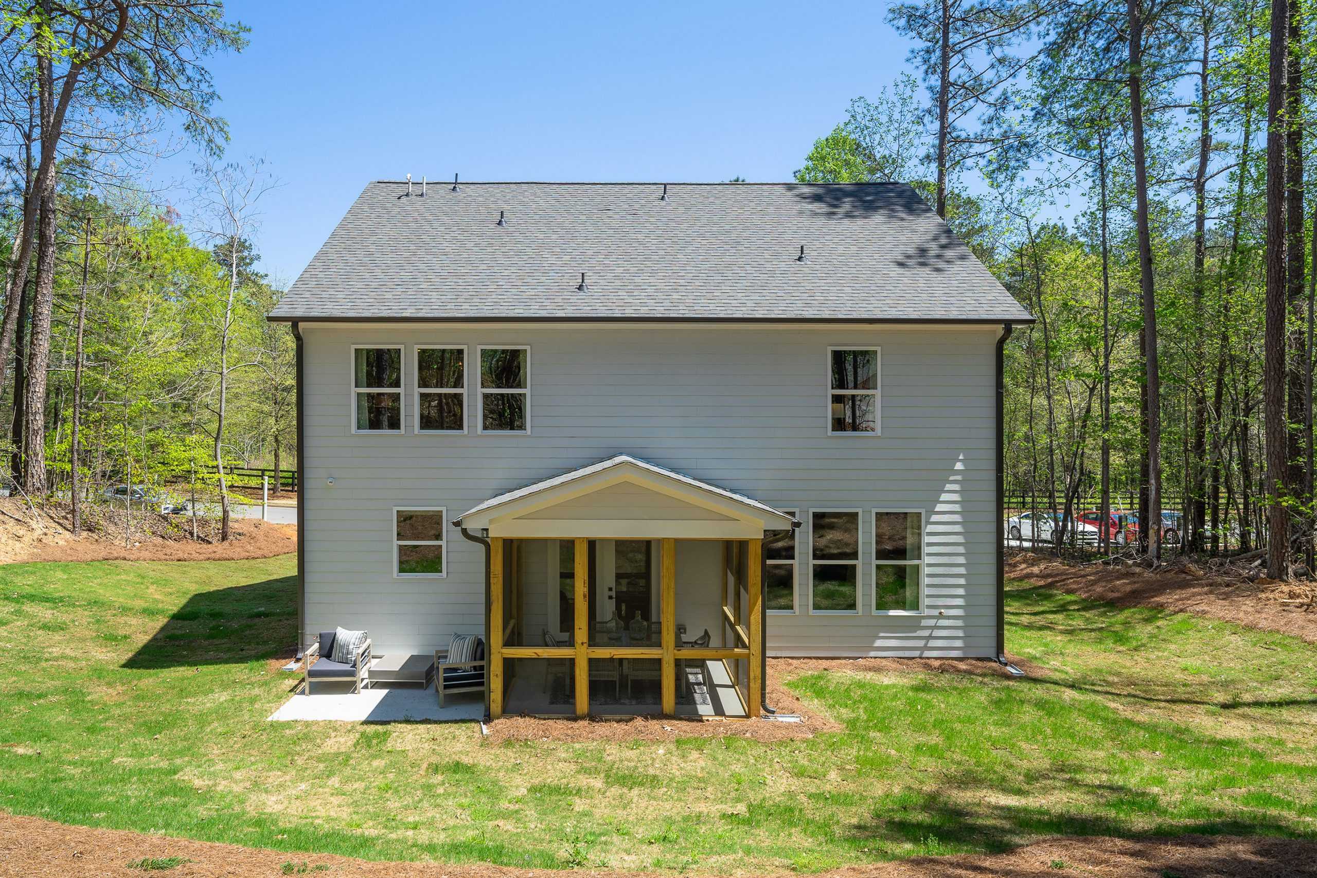 Two-story white home exterior at Riverwood in Dallas, Georgia with covered front porch, wooden seating, and surrounding pine trees